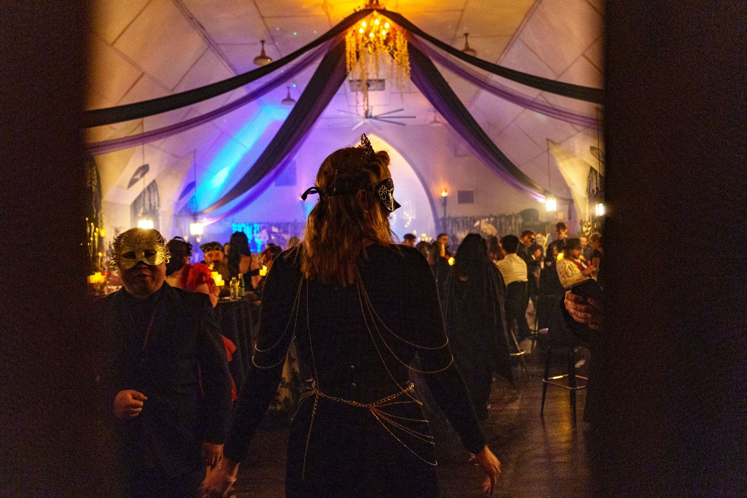 Event tent illuminated at night with colorful purple and orange lighting creating a festive atmosphere.