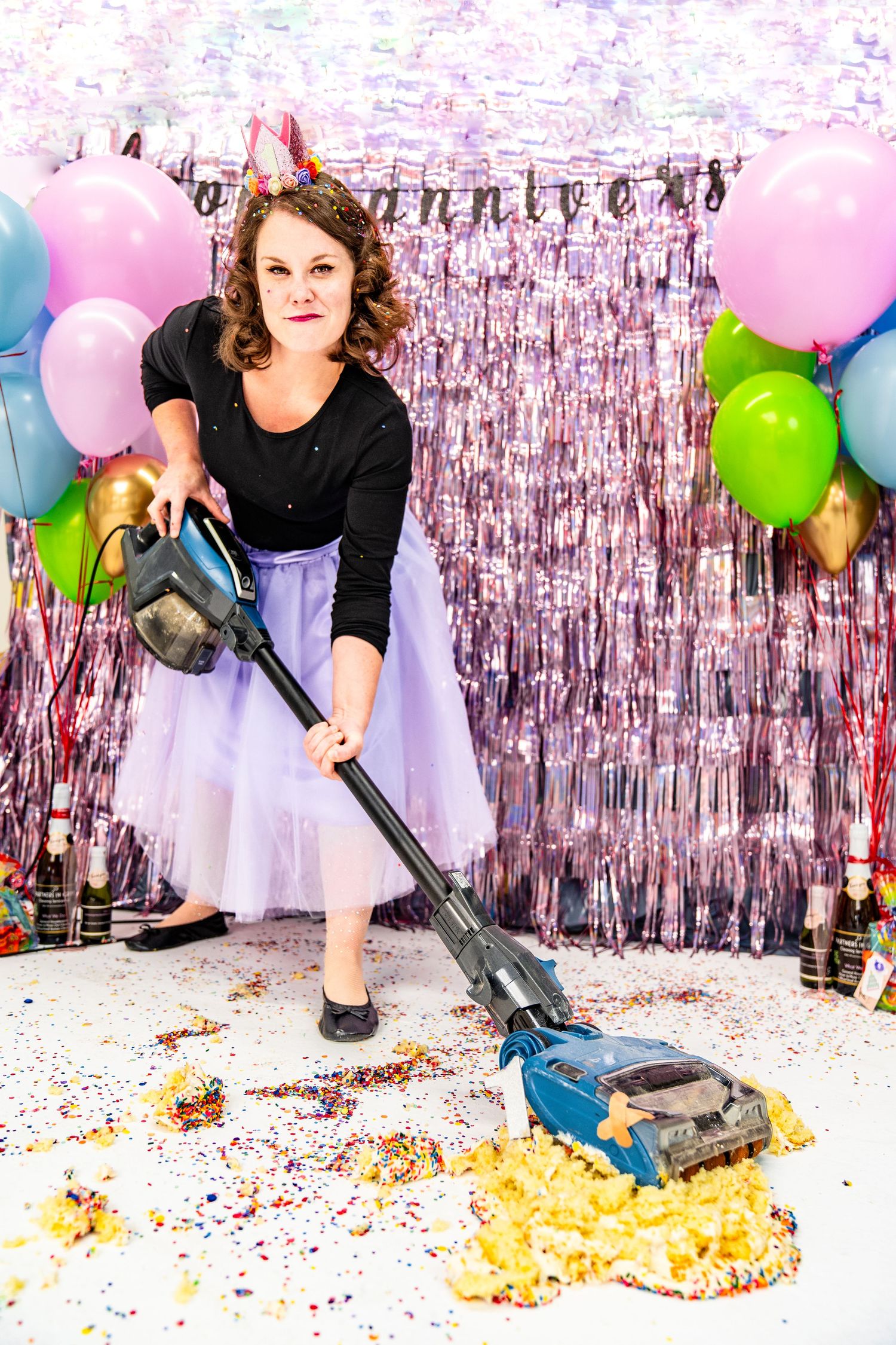 Party cleanup scene with vacuum cleaner, tulle skirt and metallic backdrop decorations.