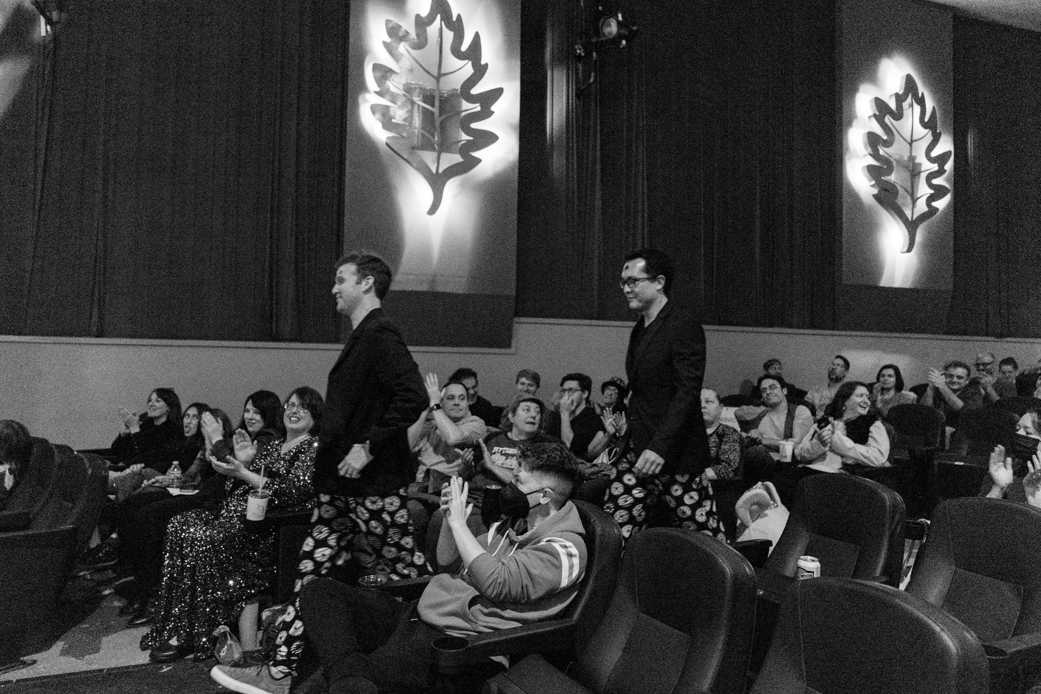 Audience members seated in rows watching presentation in darkened auditorium.