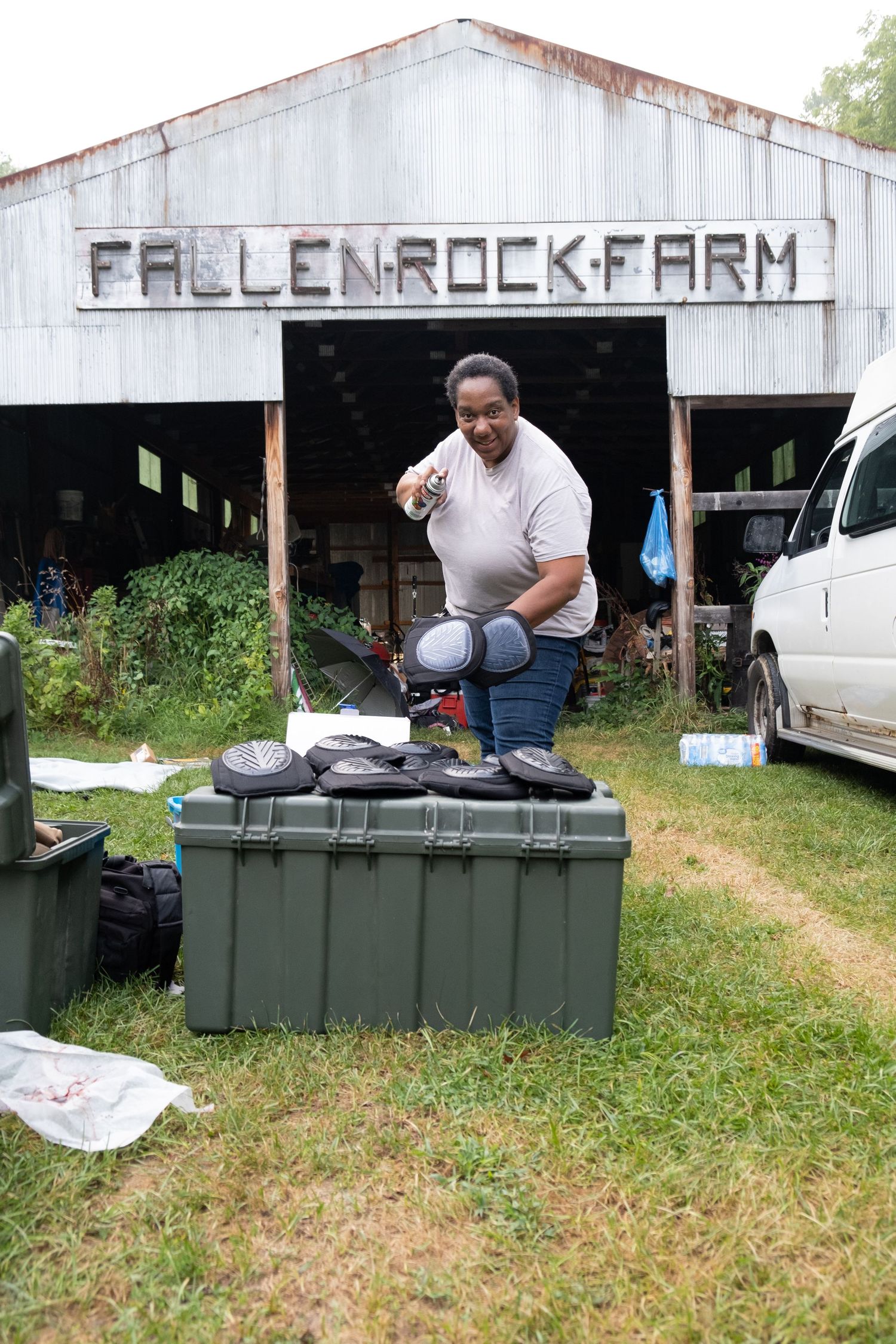 Woman standing outside Fallen Rock Farm barn with equipment cases on the grass.
