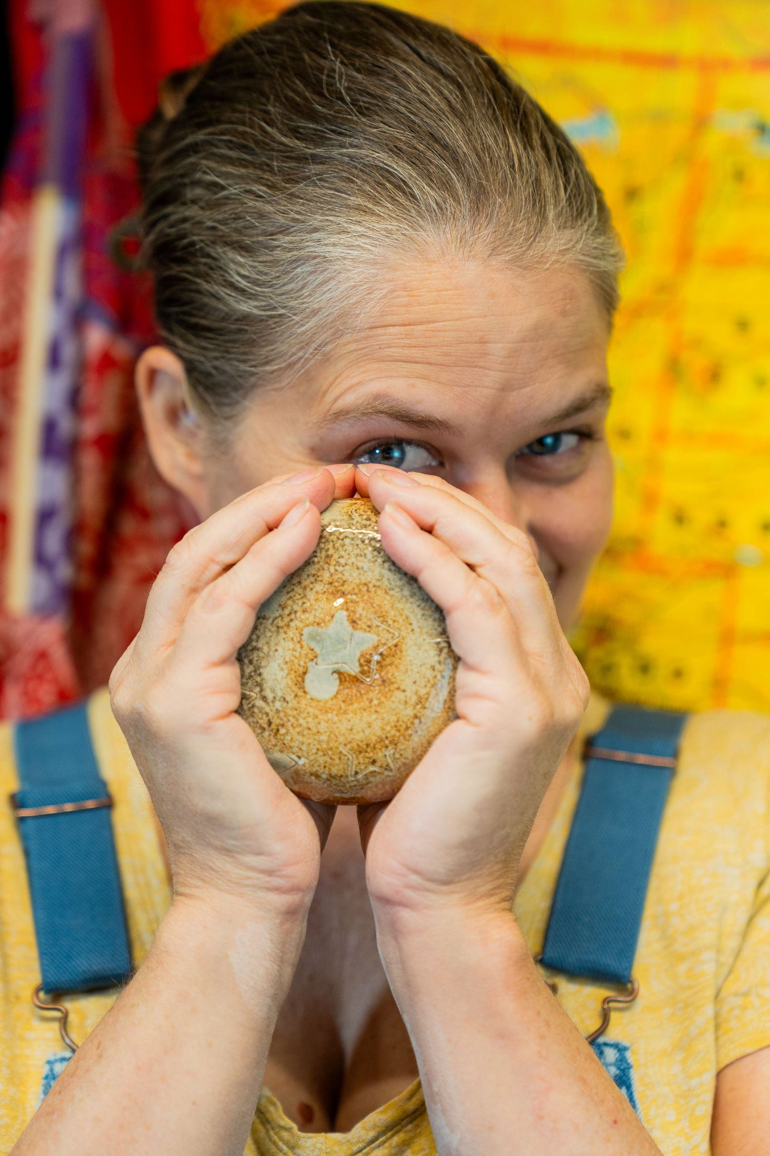 A sequence of photos showing someone playfully looking through the hole of a bagel against a yellow background.
