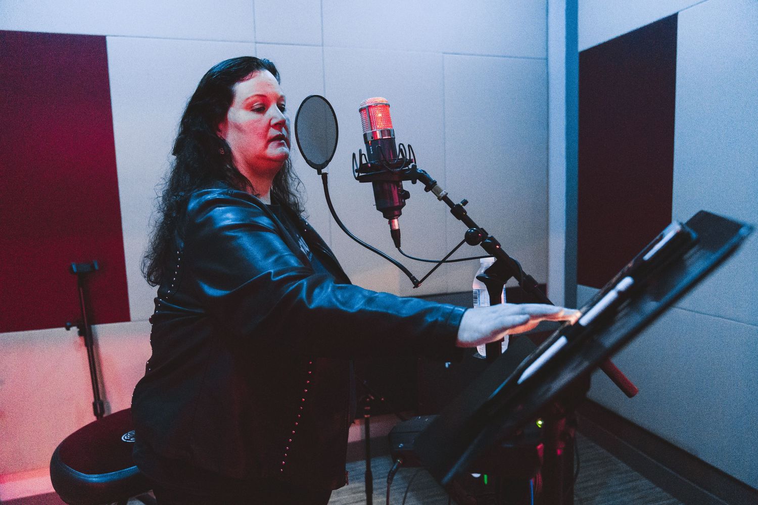 Recording session in studio with microphone and music stand.