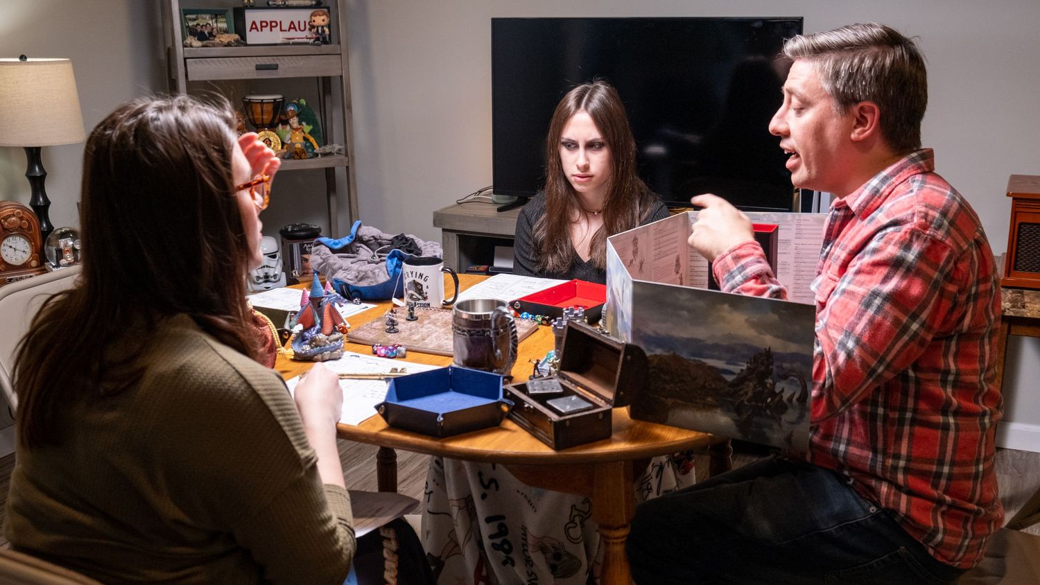 Group plays tabletop roleplaying game around a table in dimly lit room.