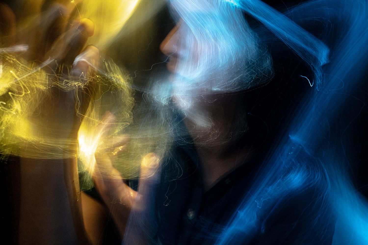 Yellow and blue light trails intertwine in an abstract cosmic pattern.