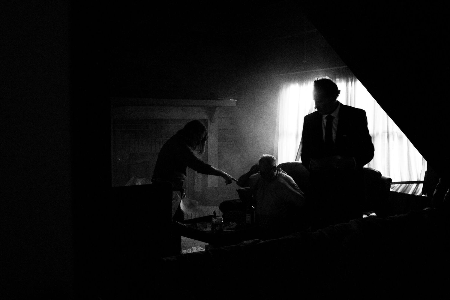 A dramatic black and white silhouette of a person working at a desk in a dimly lit room.