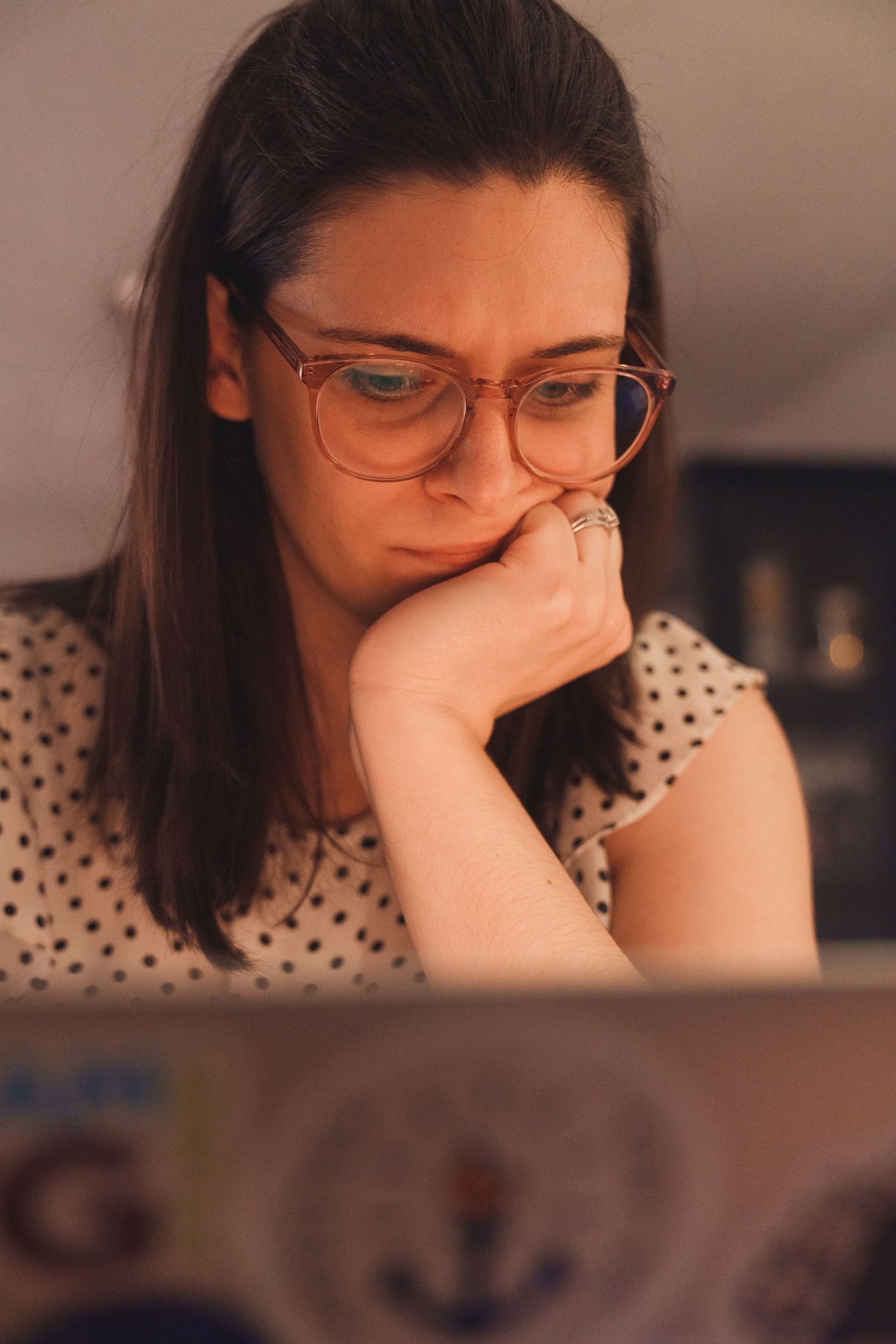 Individual in polka dot top resting head in hands while seated.