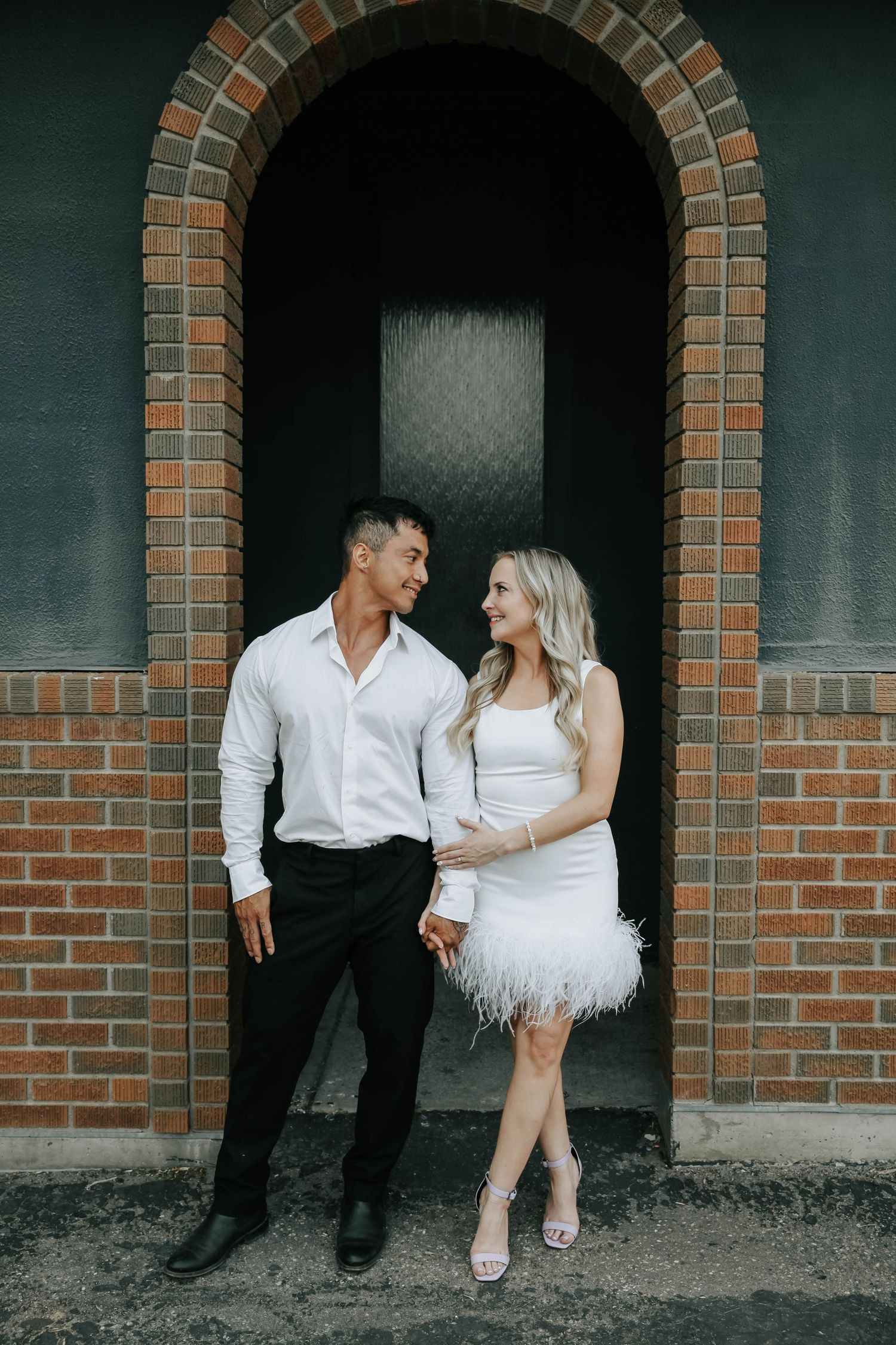 couple holding hands looking at eachother during their engagement session in downtown lethbridge alberta