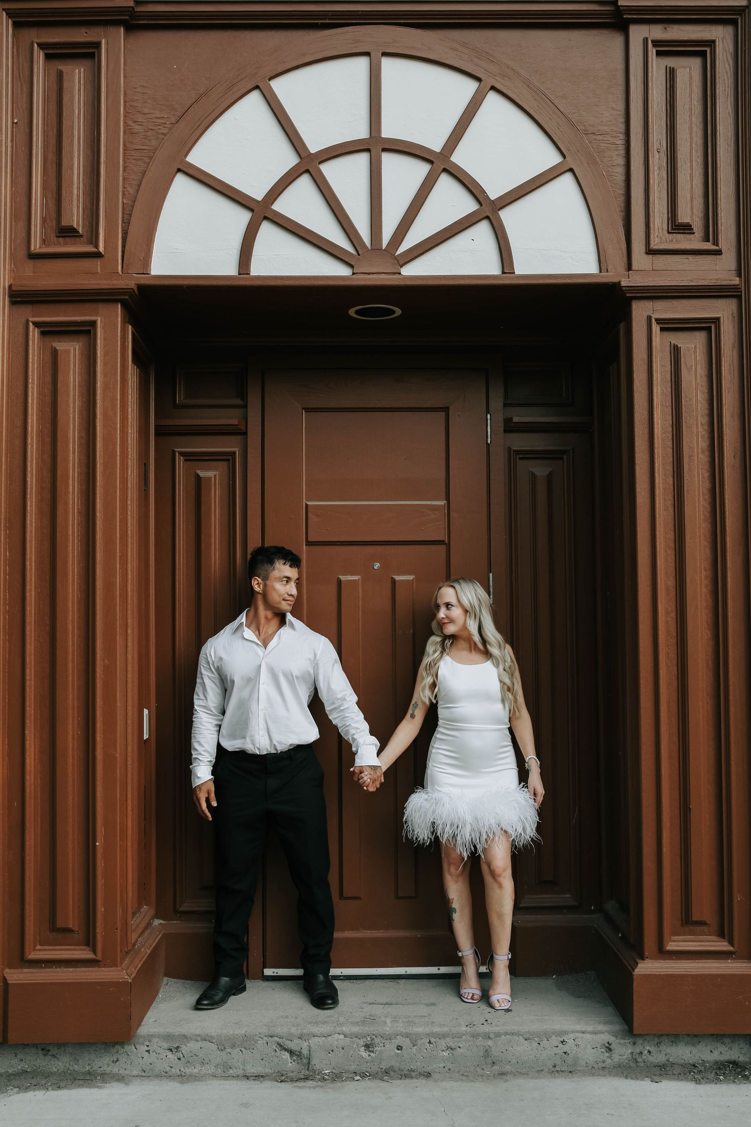 couple holding hands looking at eachother during their engagement session in downtown lethbridge alberta