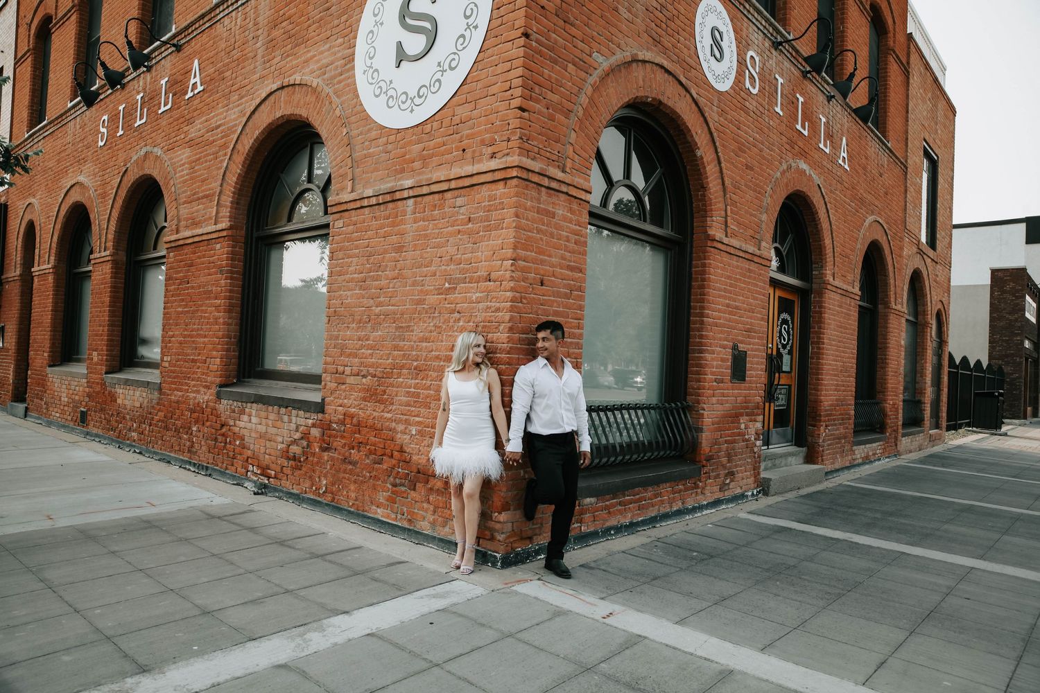 couple holding hands looking at eachother during their engagement session in downtown lethbridge alberta