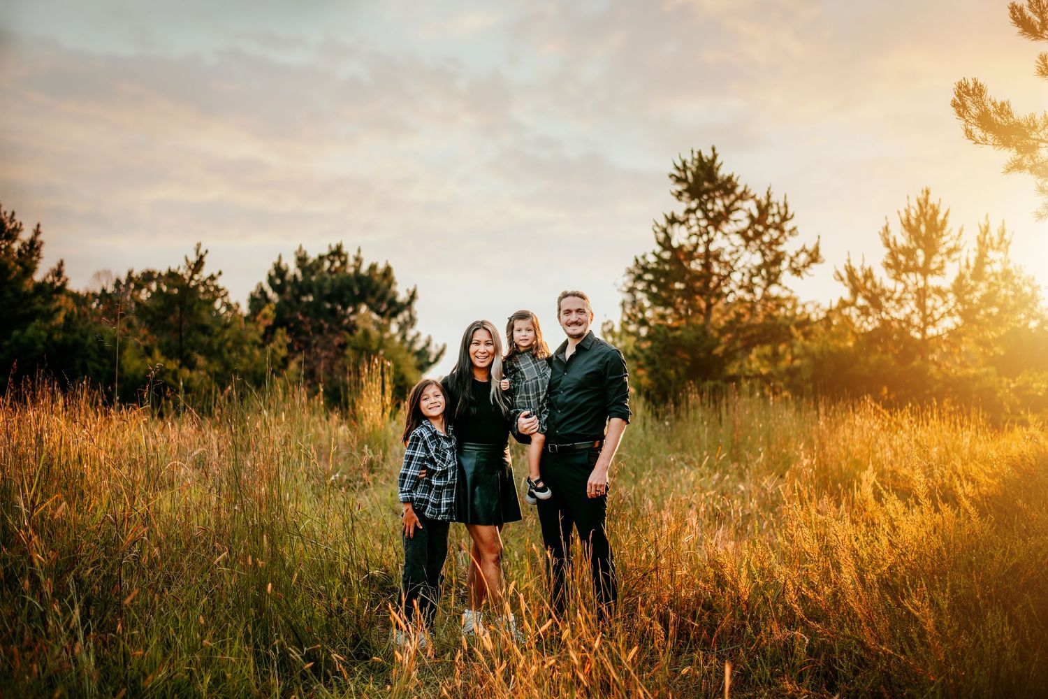 A group stands together in a golden field at sunset with warm light filtering through tall grasses.