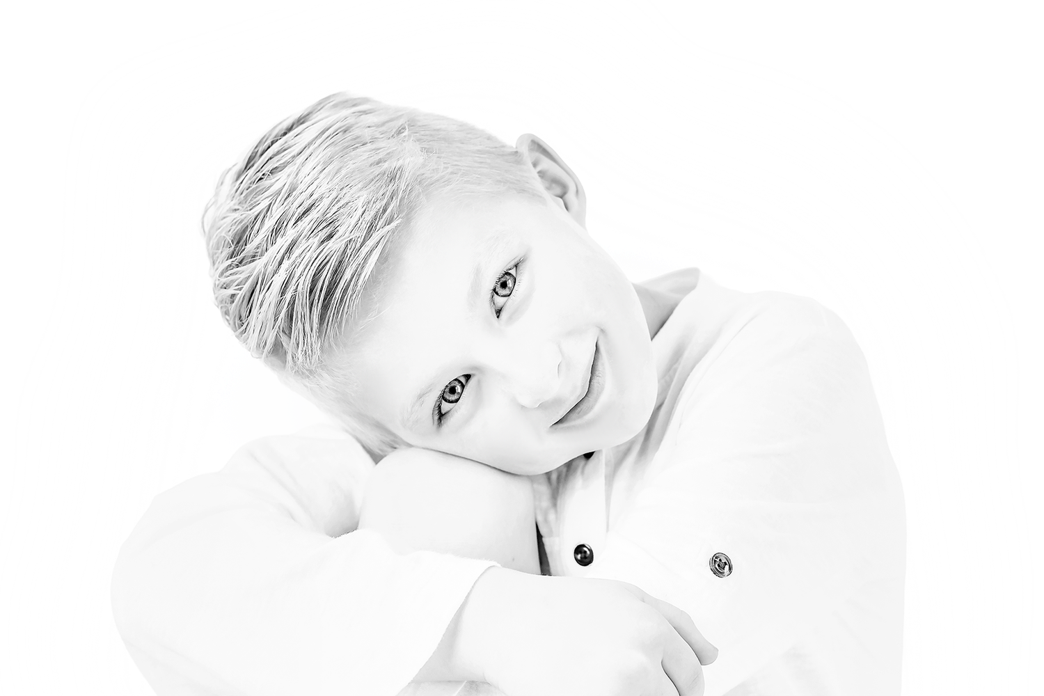 A black and white portrait photo of someone lying down with a soft, gentle expression against a light background.