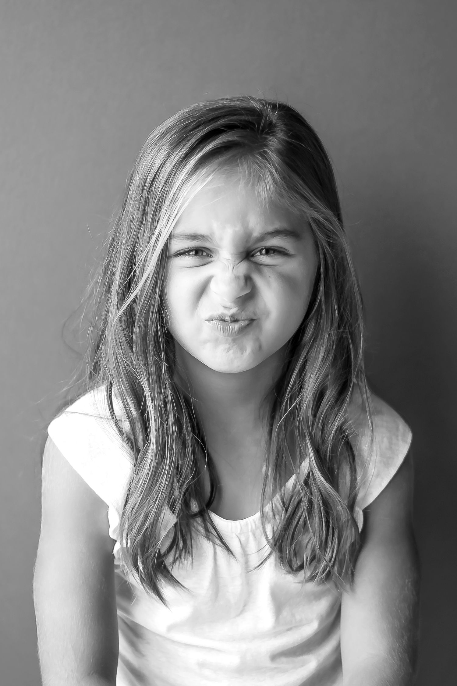 Young child making silly scrunched face expression in black and white portrait.