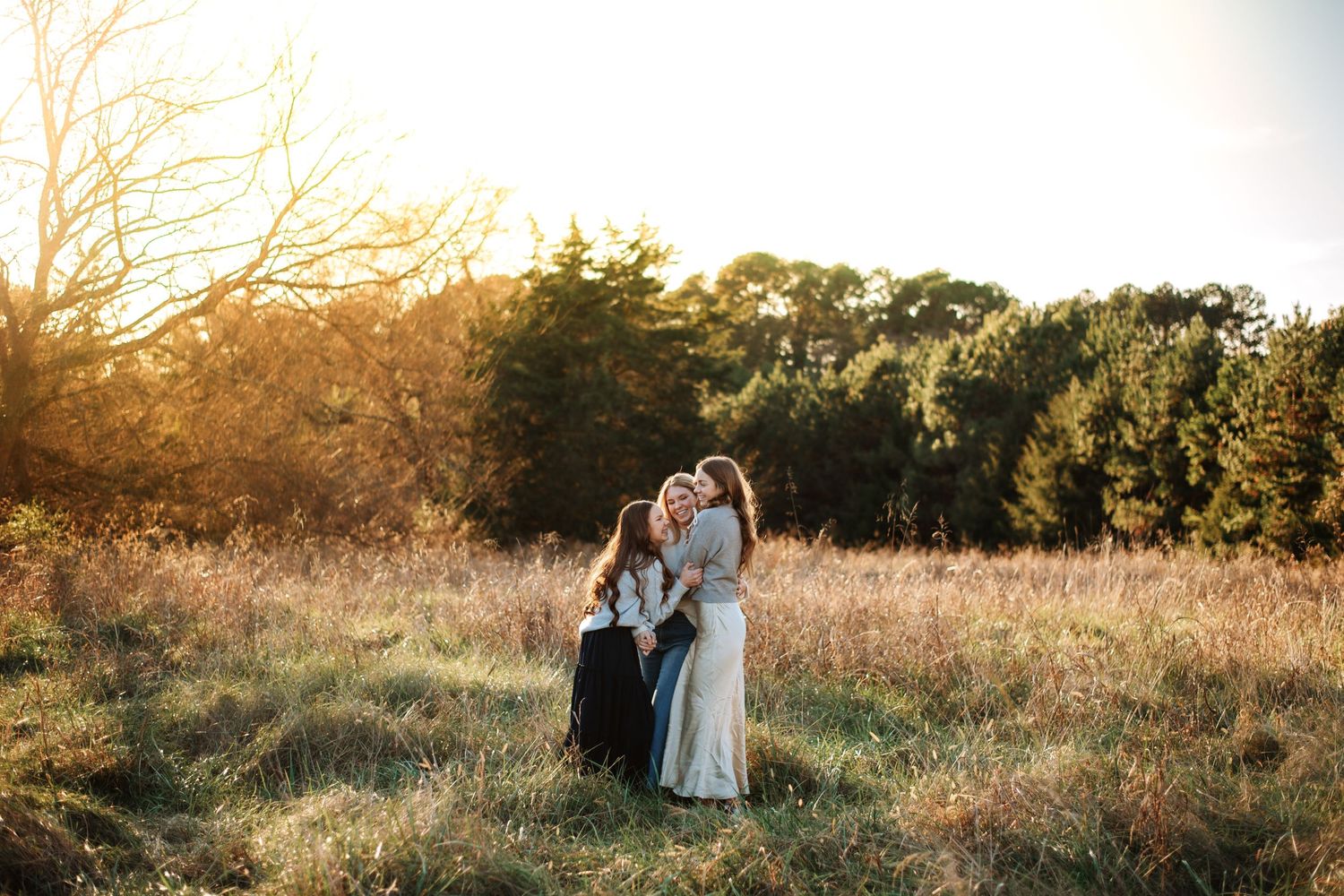 Group portrait in golden field at sunset with moody lighting and natural backdrop.
