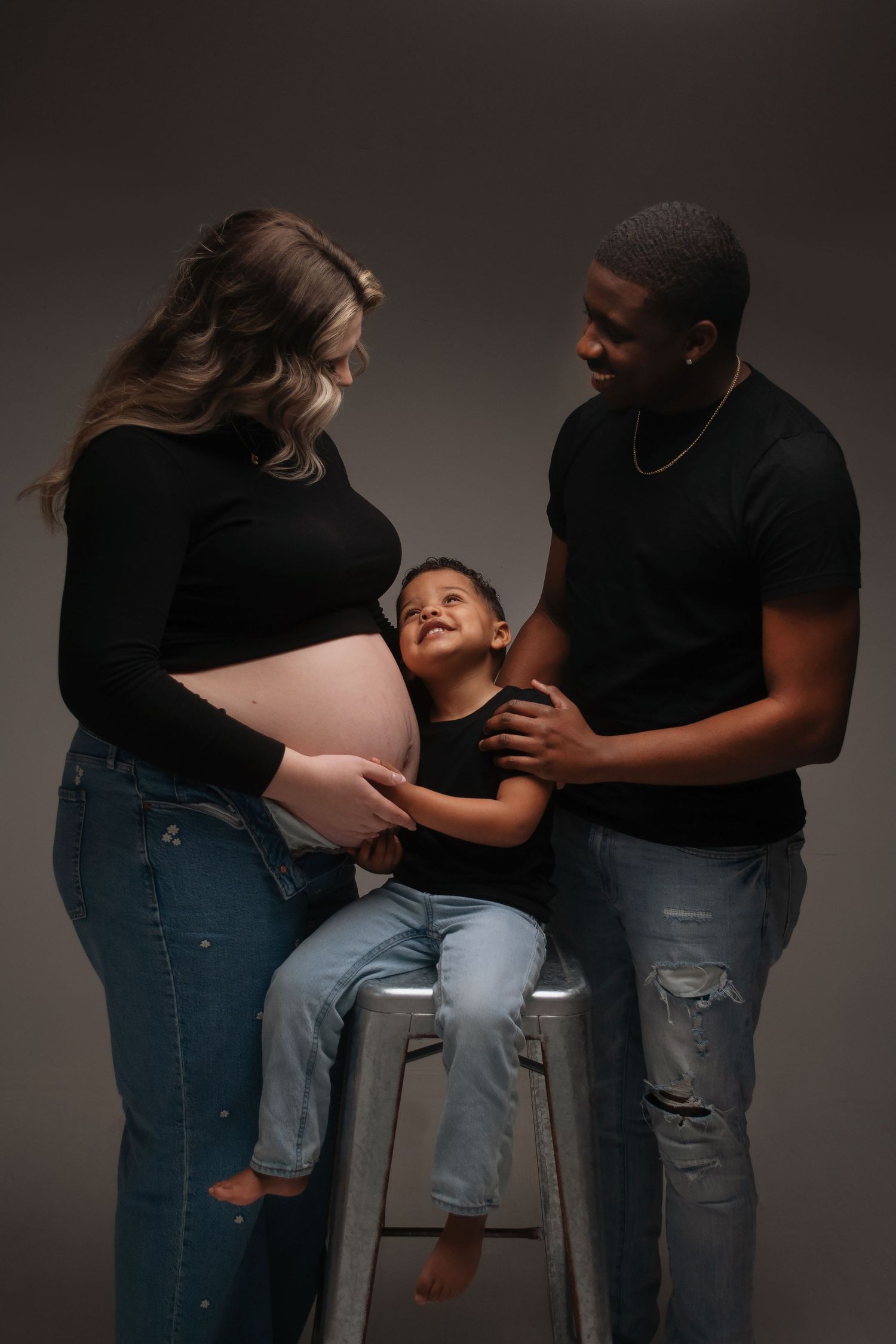 Intimate maternity portrait of expecting parents sharing a tender moment with their child.