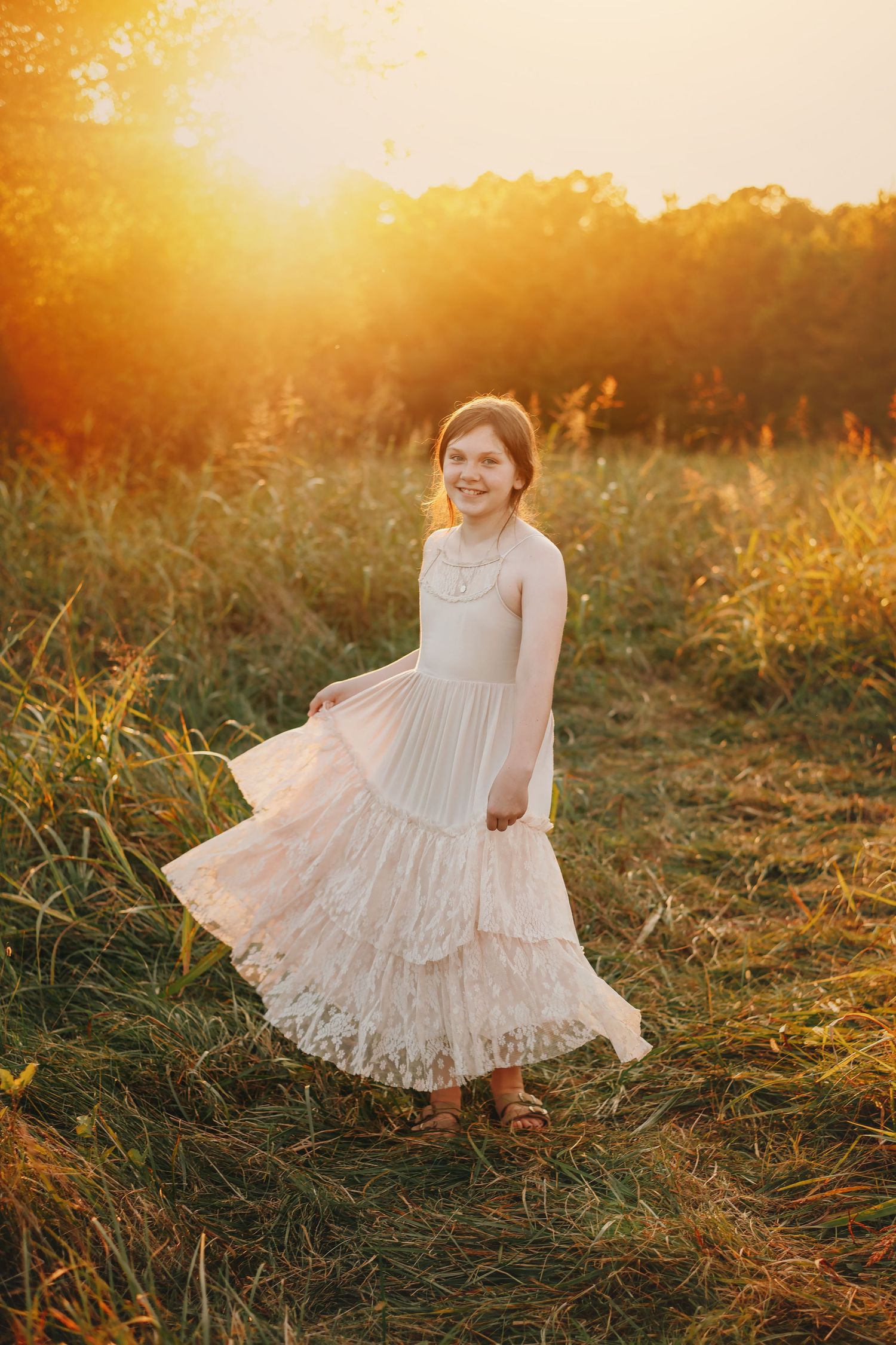 Young person in white lace dress twirling in sunlit field at golden hour in Mooresville NC.