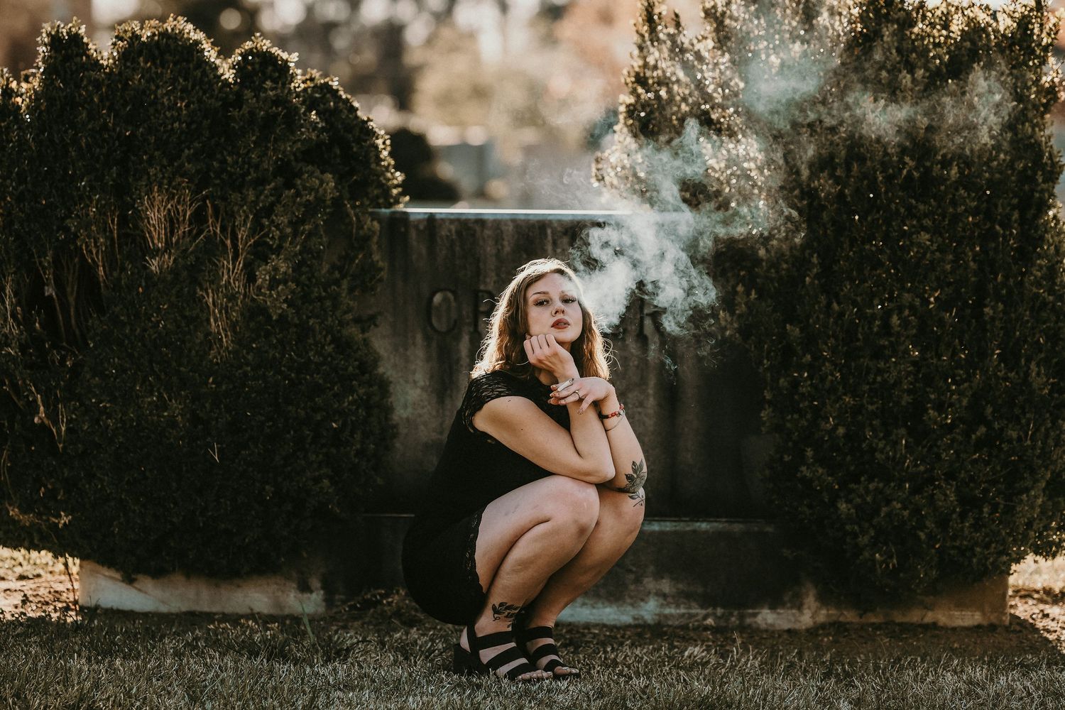 Artistic portrait with smoke effects against concrete wall backdrop.
