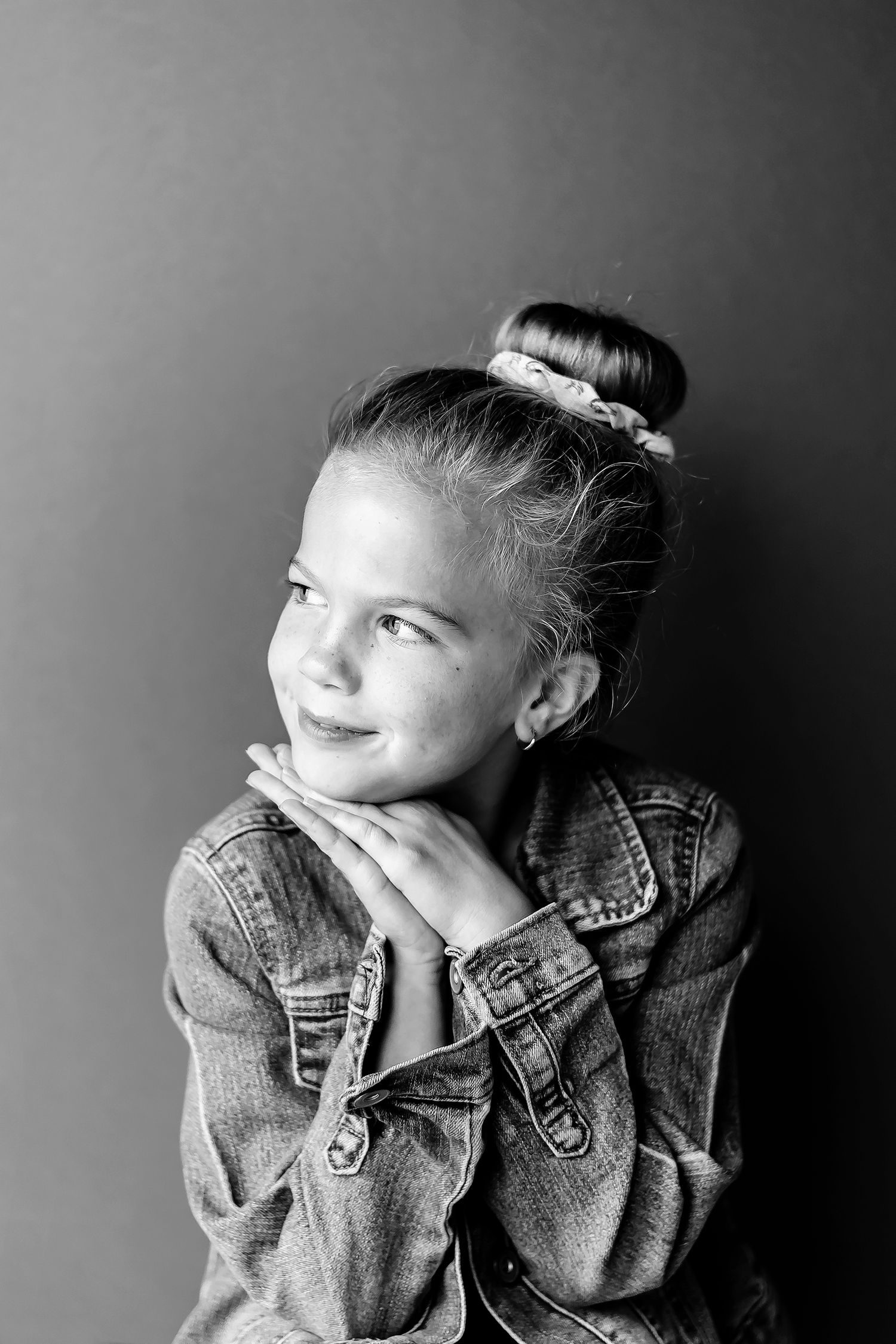 Black and white portrait in denim jacket with dreamy expression.