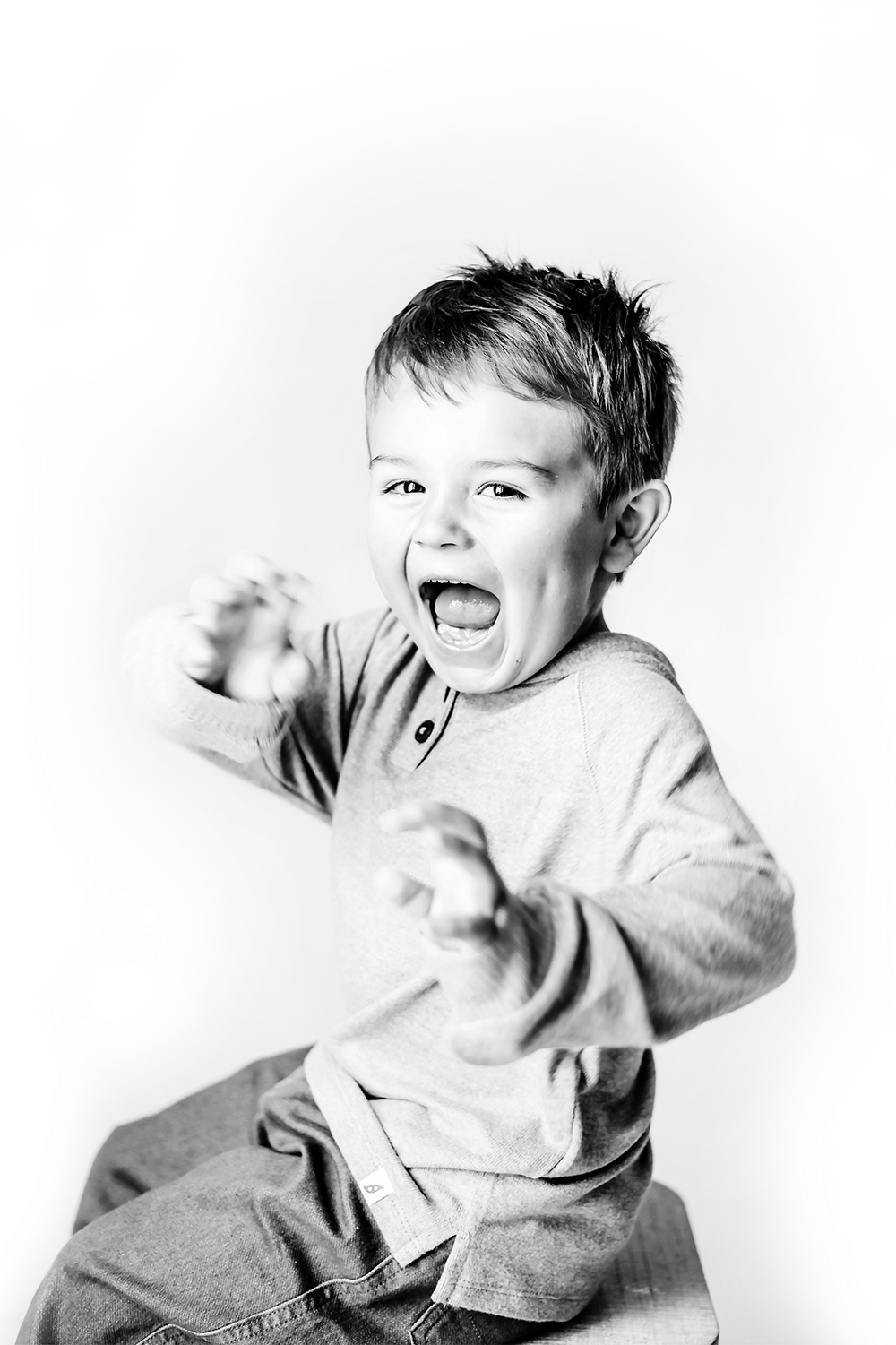 Black and white photo sequence showing a laughing child in a sweater expressing joy and amusement.