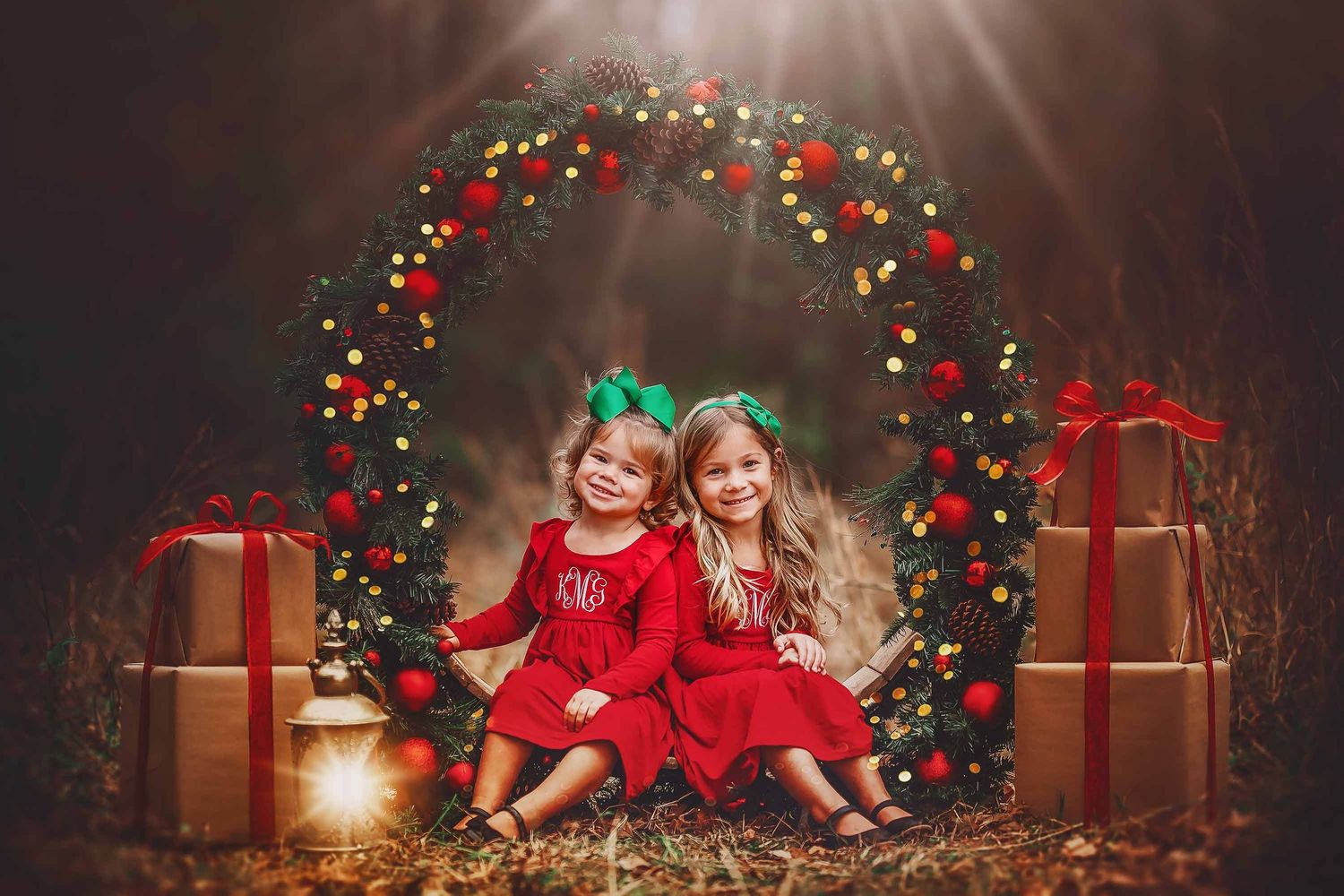 Children in red holiday outfits lie on floor surrounded by Christmas lights, presents and festive decorations.