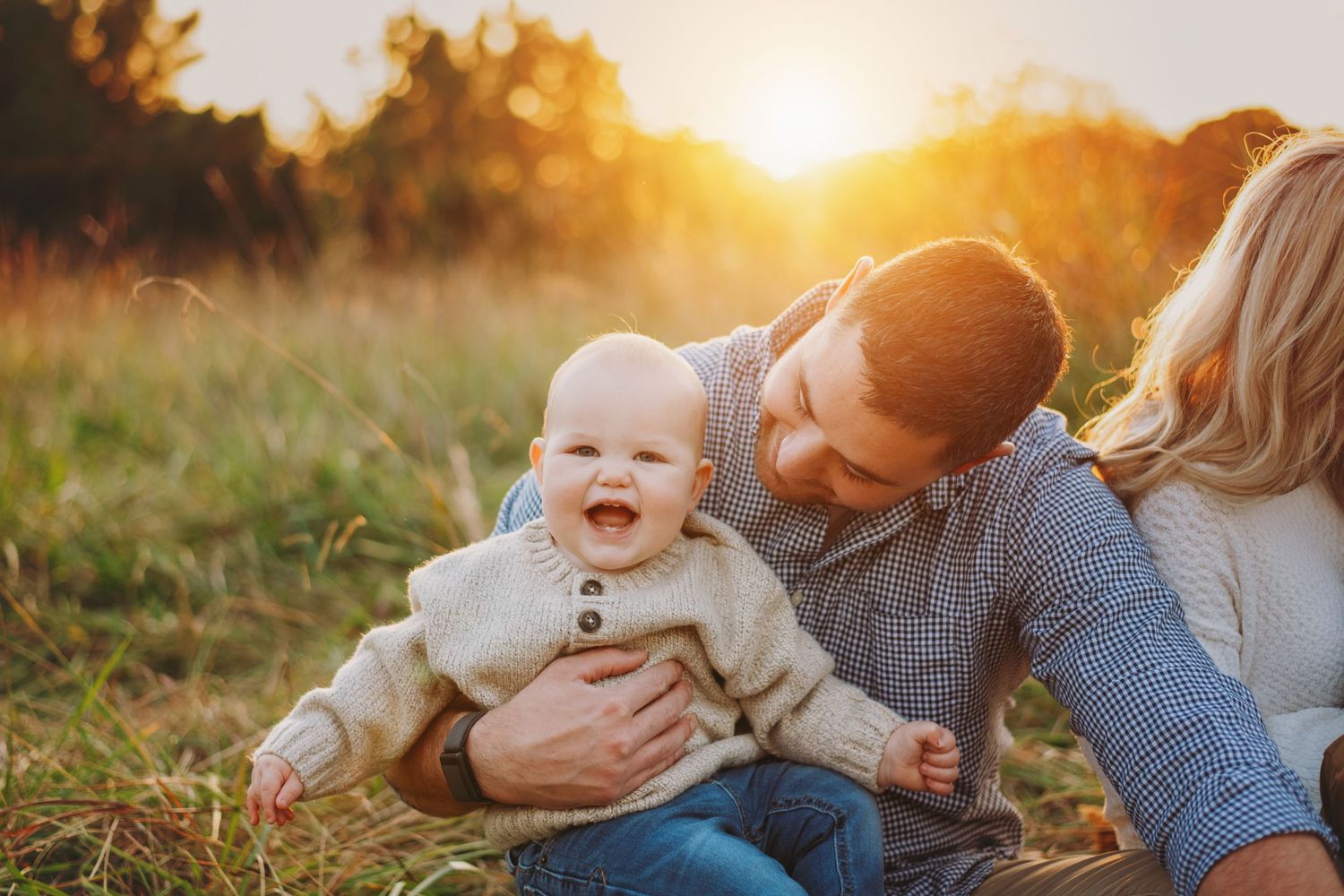 Joyful family interaction in a field during sunset with golden lighting.