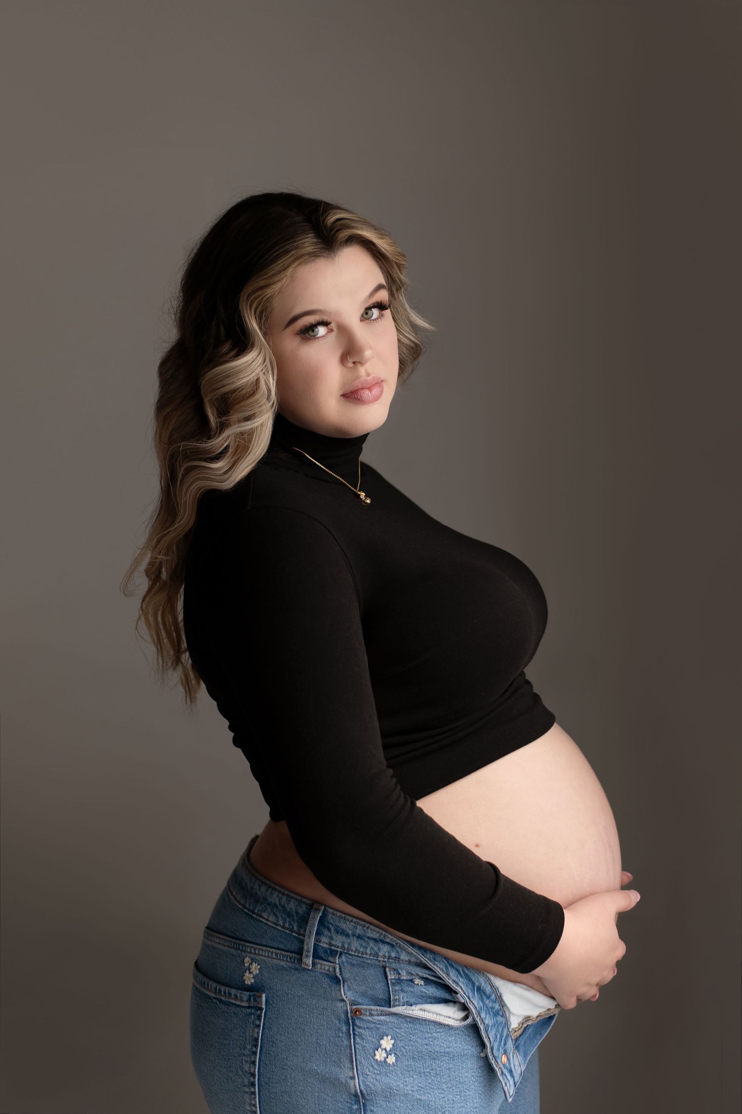 Studio portrait against grey background showing maternity style.