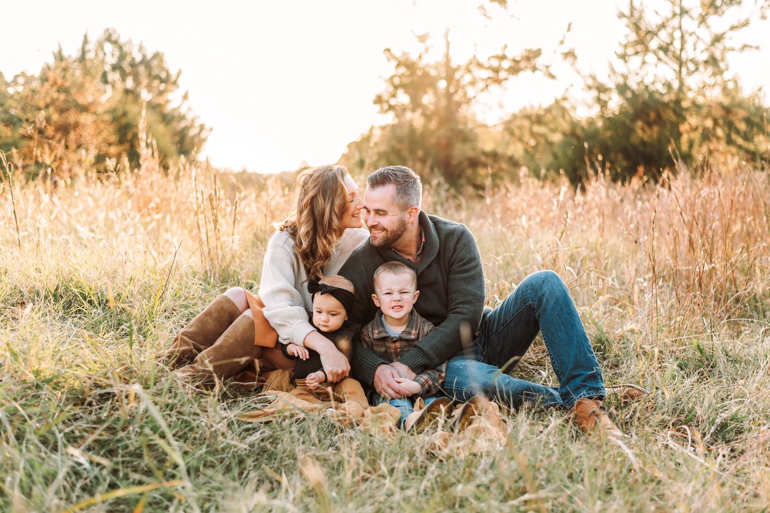 Candid family portrait with genuine laughter in golden autumn meadow.