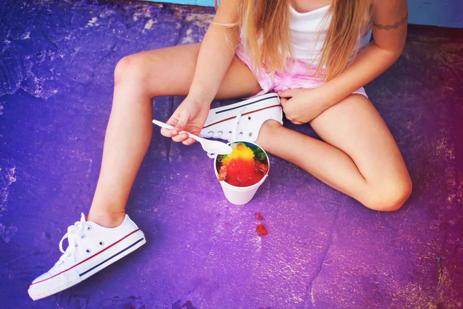 White sneakers and legs sit against a purple background in a creative photo series showing different playful poses.