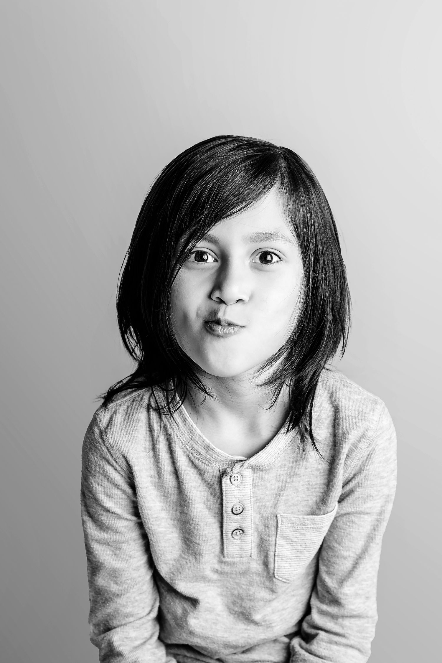 Black and white portrait series showing playful expressions in a light gray henley shirt.