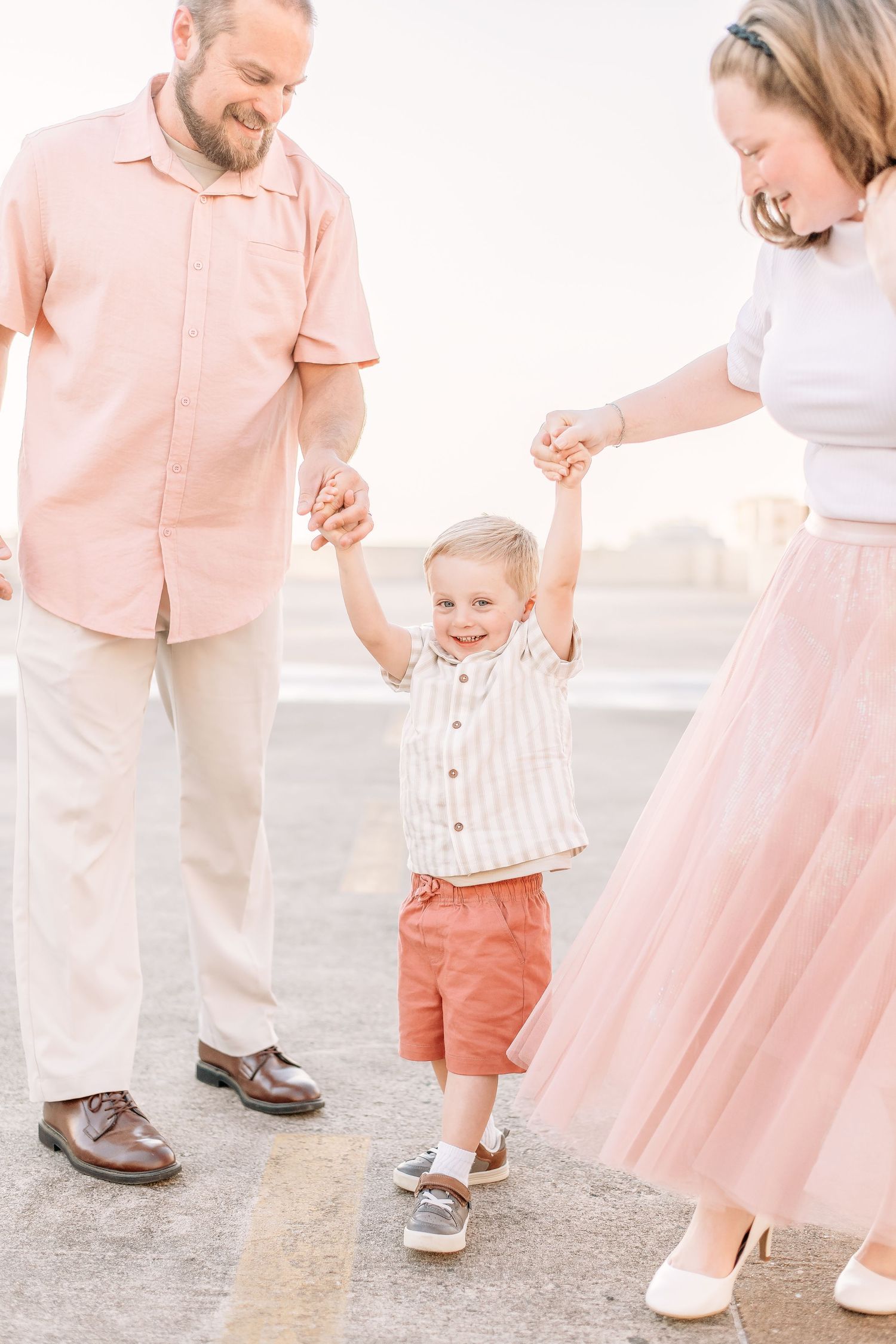 Family dressed in coordinating pink and white outfits walking together on a concrete surface.