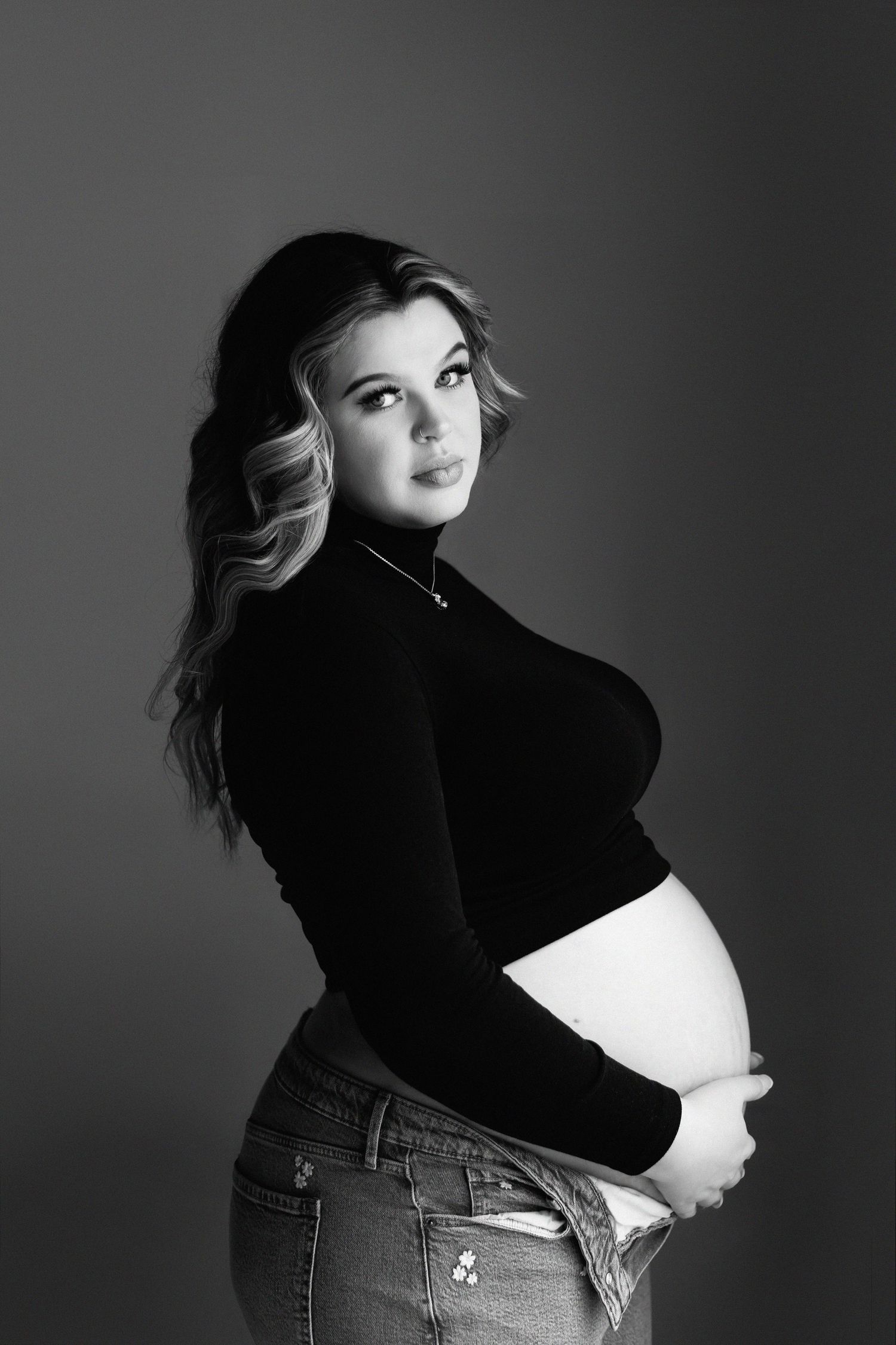 Black and white maternity portrait showing profile view in dramatic lighting in Mooresville NC studio.