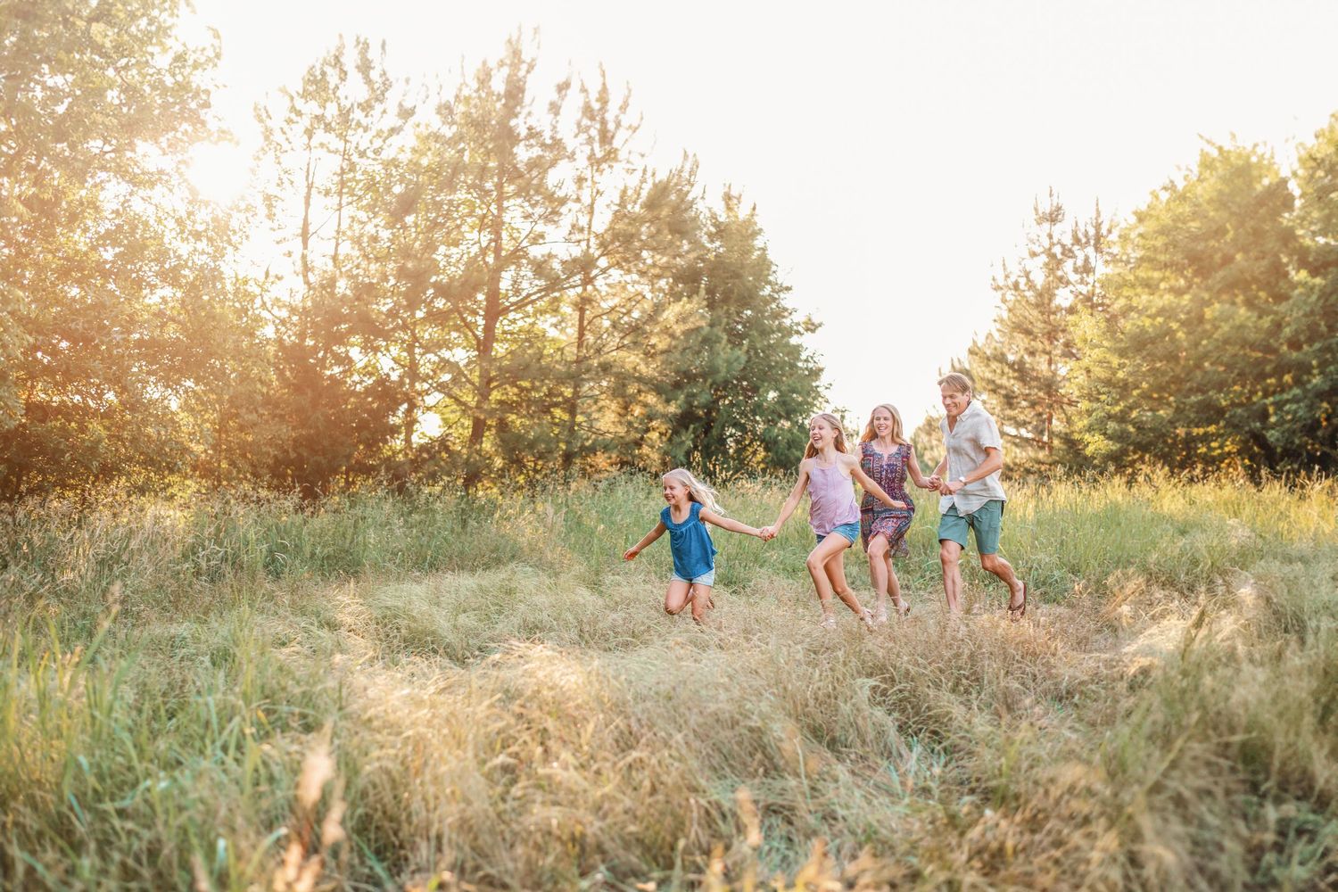 A happy group runs together through a sunlit meadow on a summer evening.