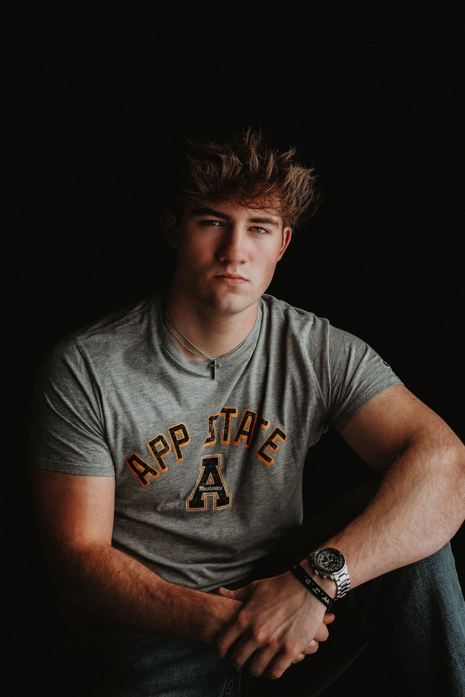 Student wearing App State t-shirt photographed against dark background.