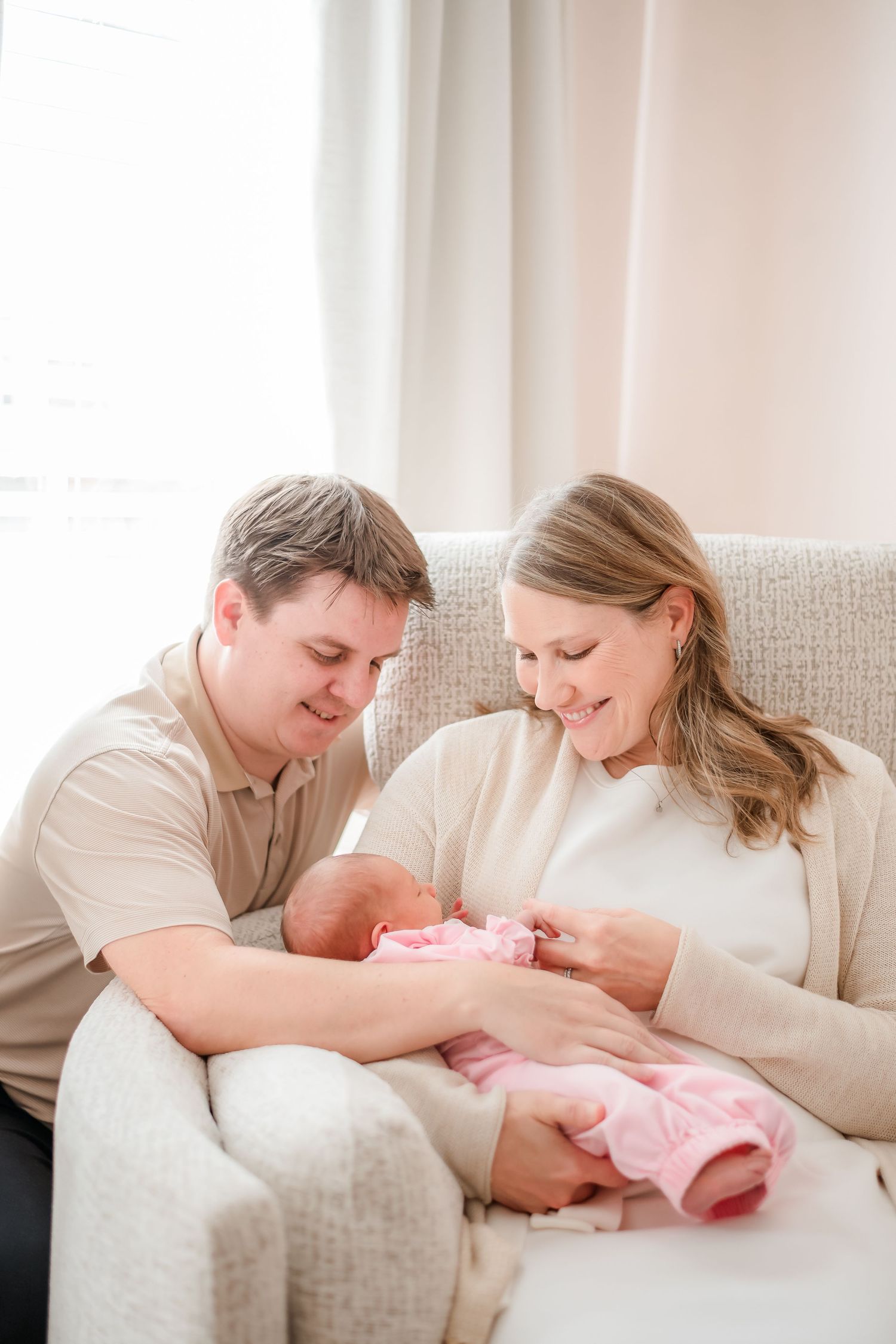 A tender family moment shared on a beige couch with a newborn baby.