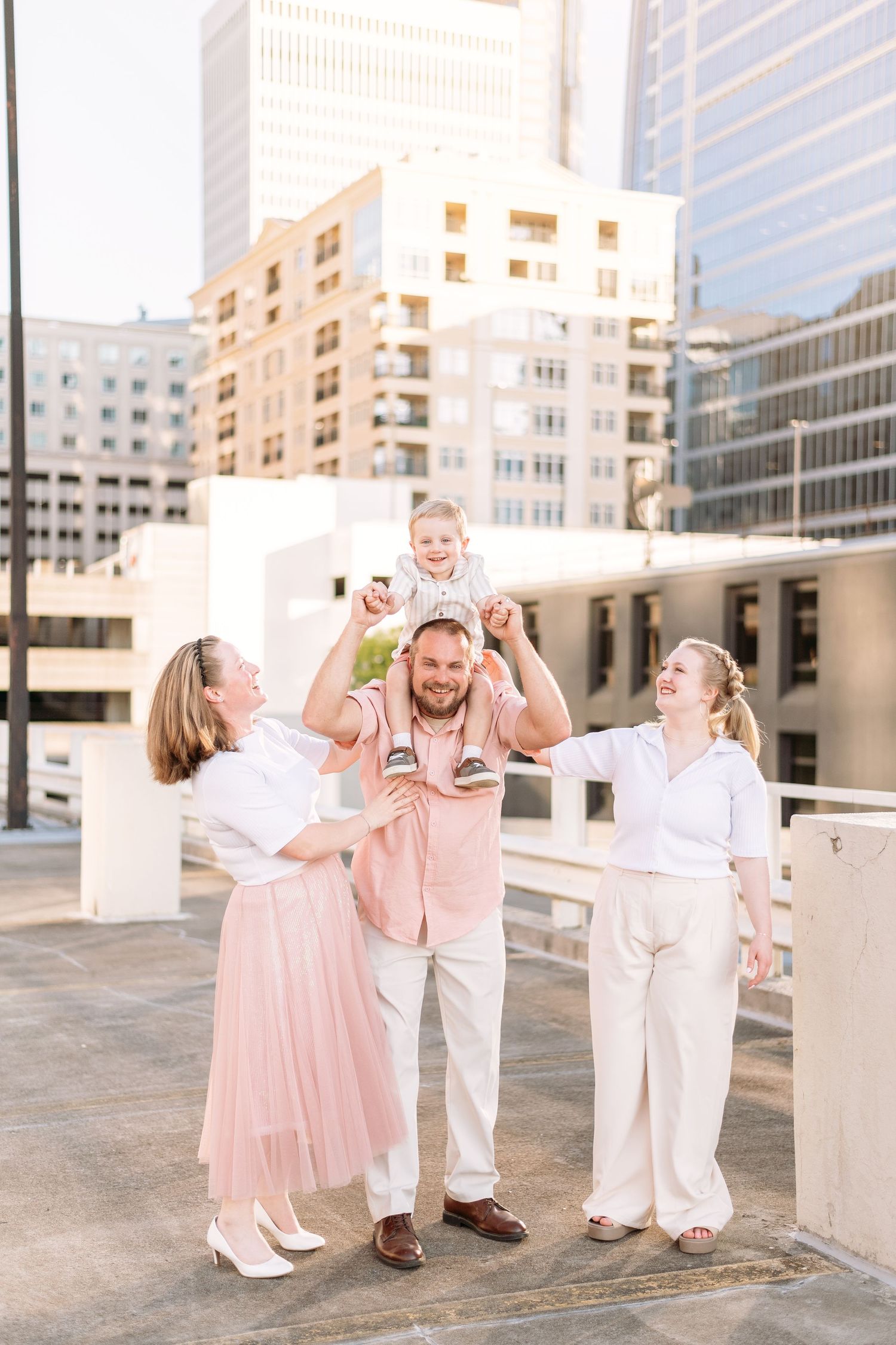 A playful family photoshoot featuring coordinated pink and white outfits on an urban rooftop.