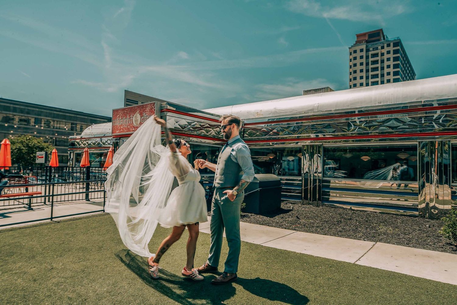 Bride and groom share a romantic moment outdoors on a rooftop venue on a sunny wedding day.