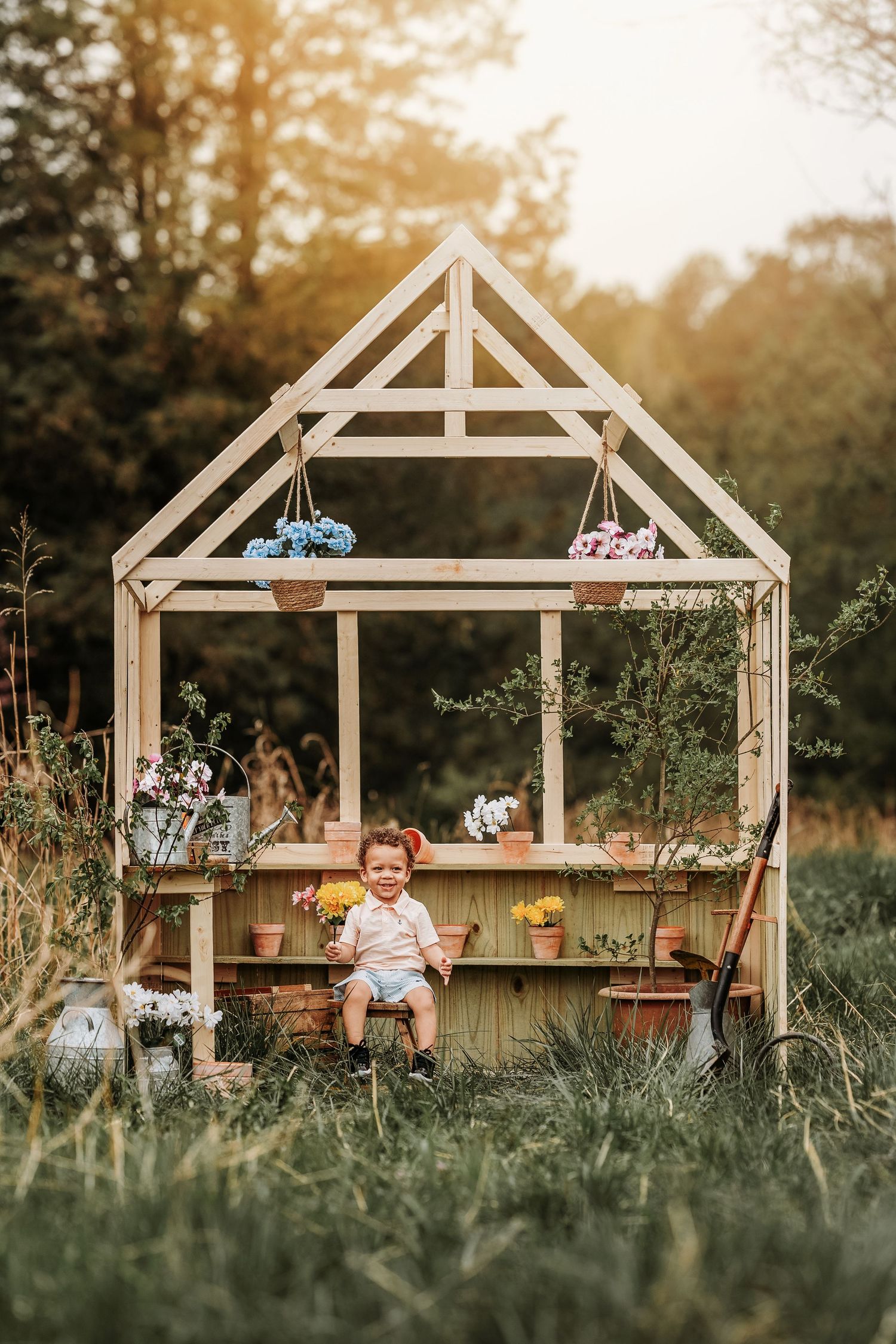 Wooden garden playhouse frame progression showing construction stages in golden sunset light with natural landscaping.