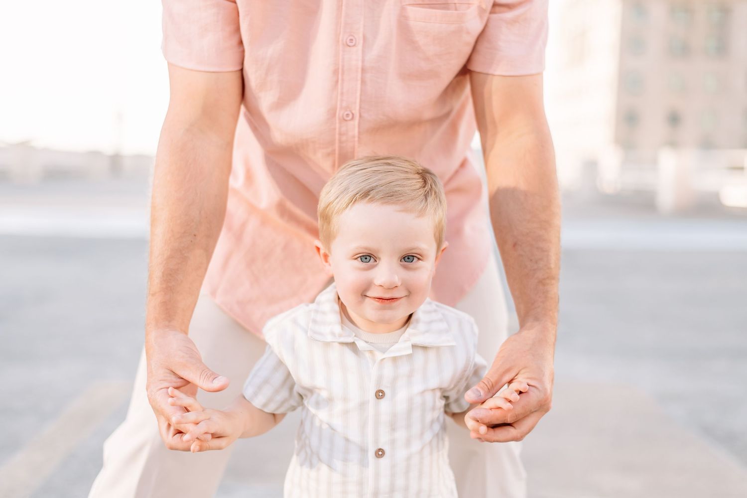 A sweet family moment captured in soft pink tones on a city rooftop.