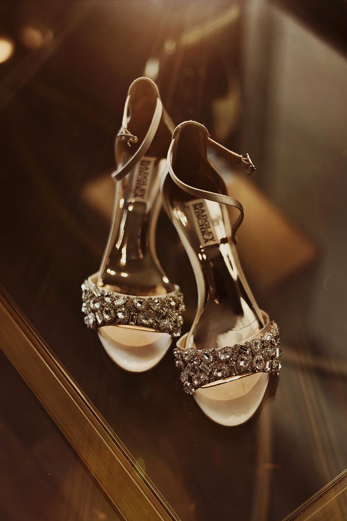 Elegant Badgley Mischka bridal heels adorned with sparkling crystal embellishments on a reflective gold surface.
