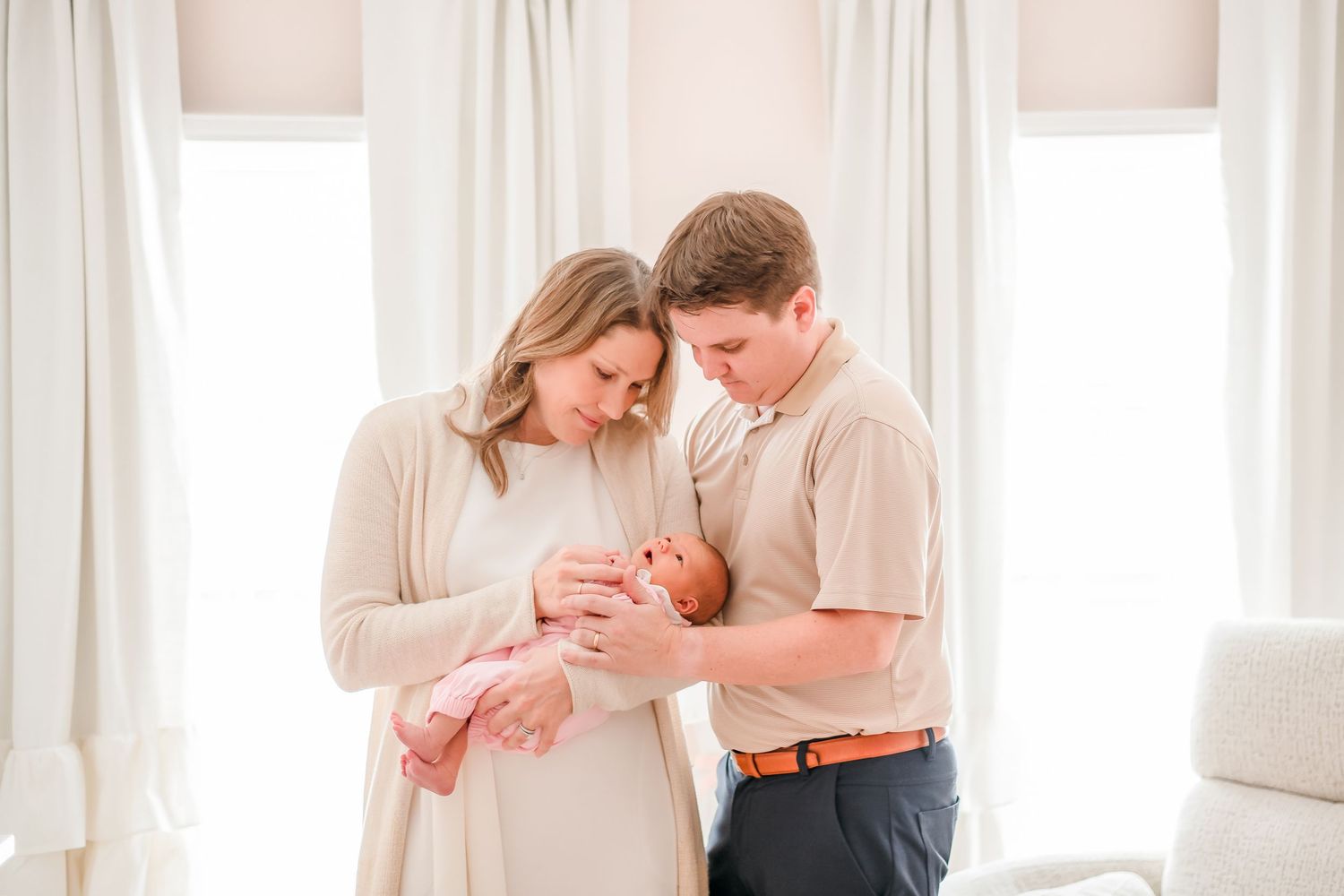 A tender family moment with a newborn baby in a bright, sunlit room.