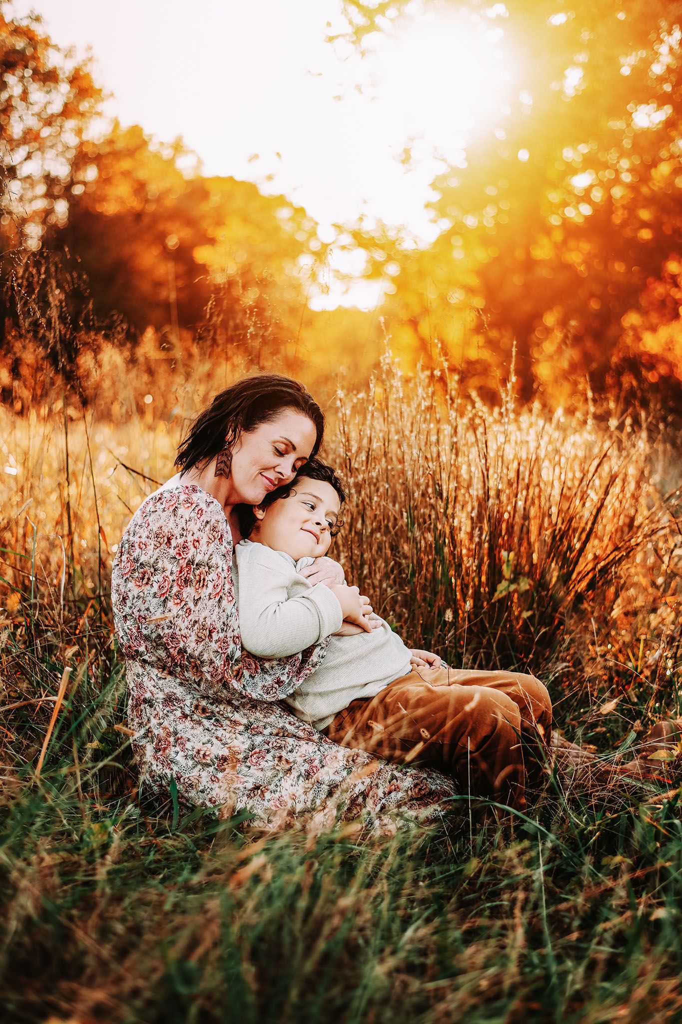 Mother and child embracing in golden autumn field at sunset, warm fall colors surrounding them.