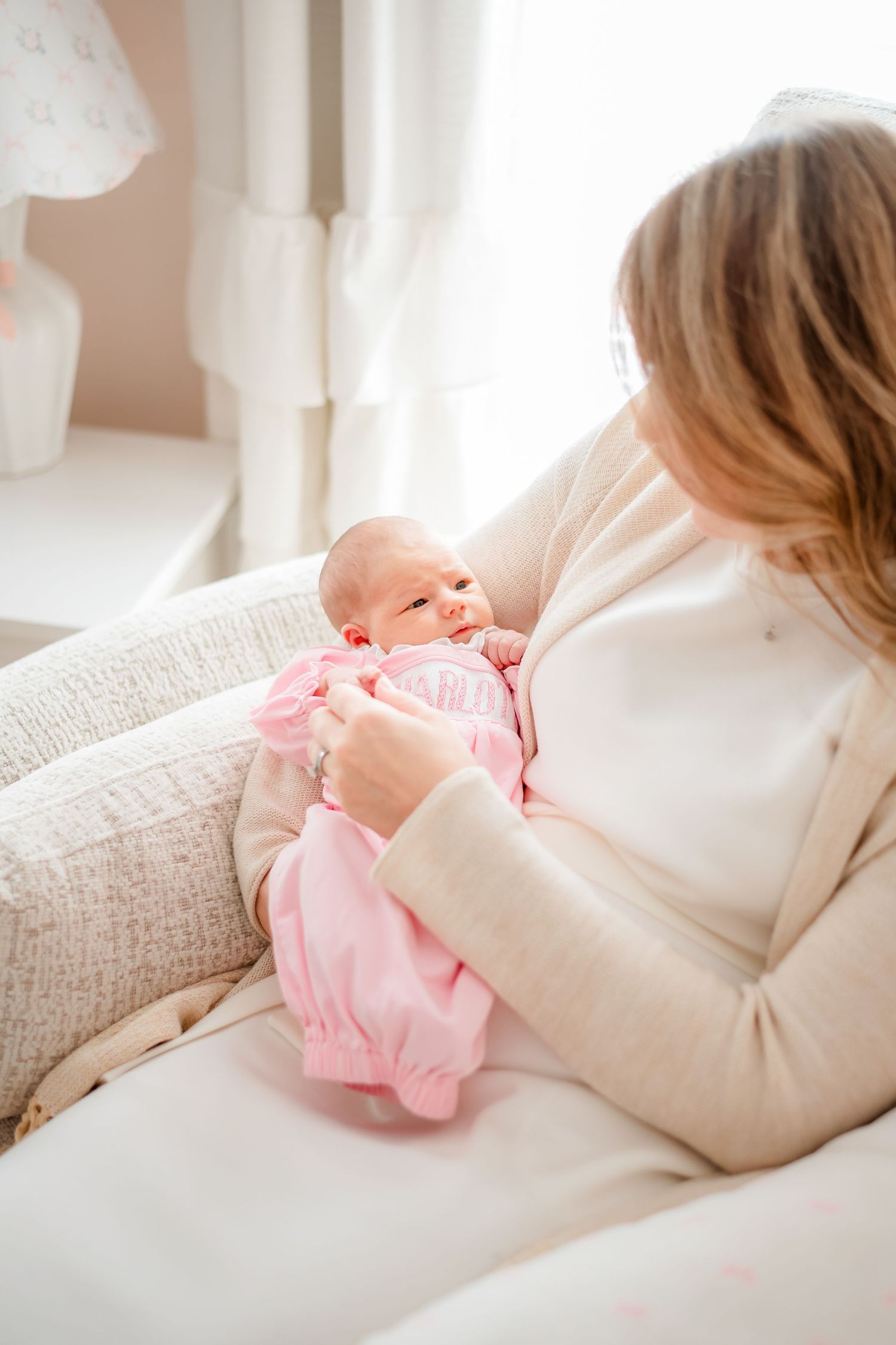 A peaceful moment with a newborn baby dressed in pink resting on a cozy chair.