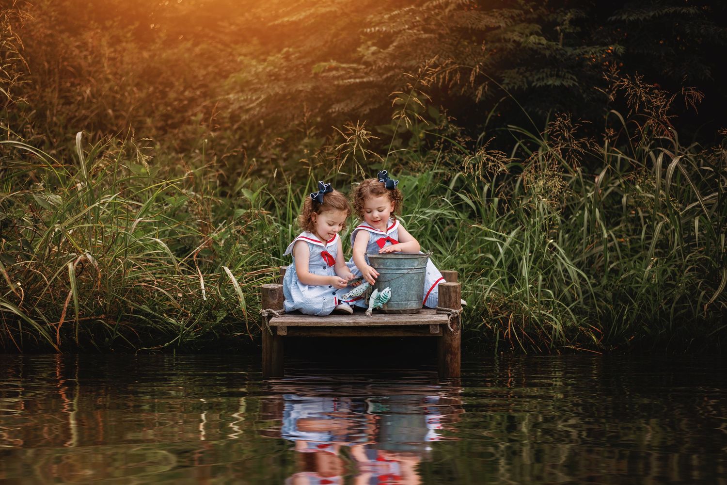 Two people sit in a canoe on a tranquil lake surrounded by tall grasses during golden hour.