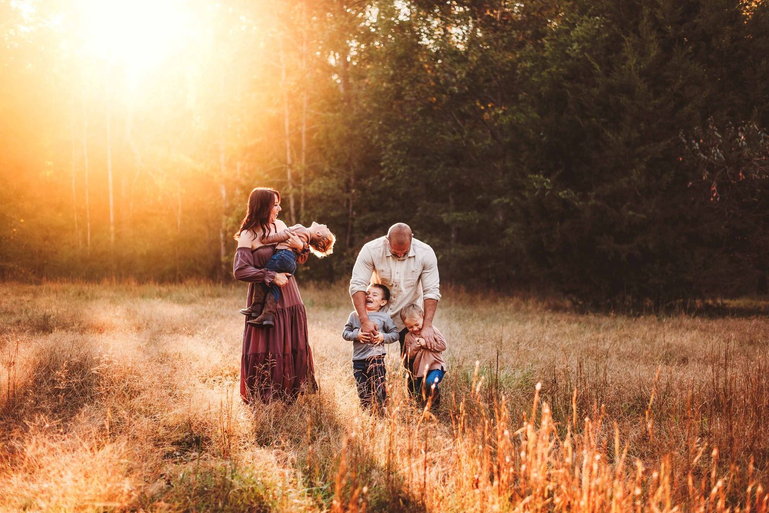 Family silhouettes walk through a golden field at sunset in Mooresville NC