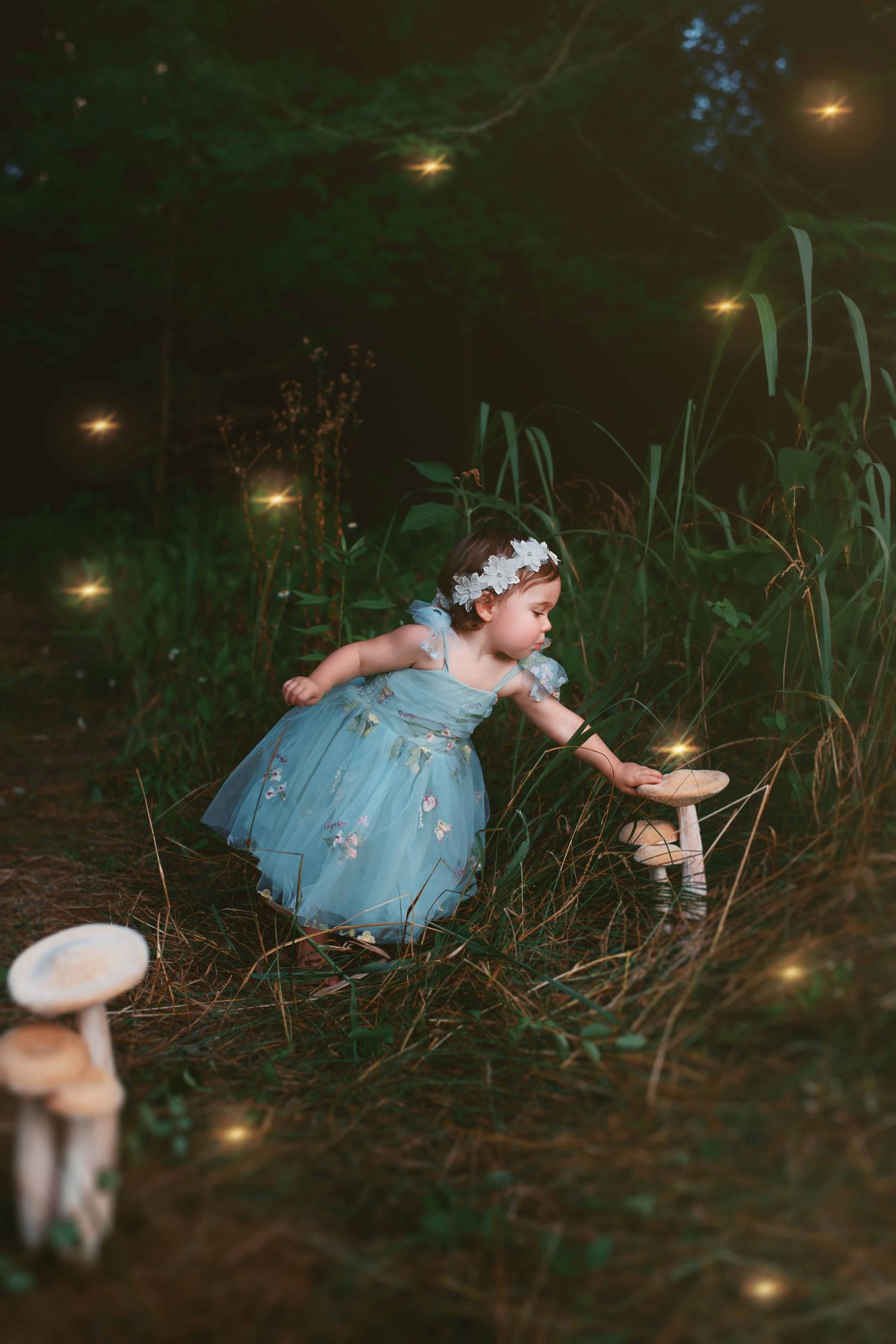 Magical nighttime scene with a small figure in a blue dress reaching towards glowing lights in a dark garden setting.