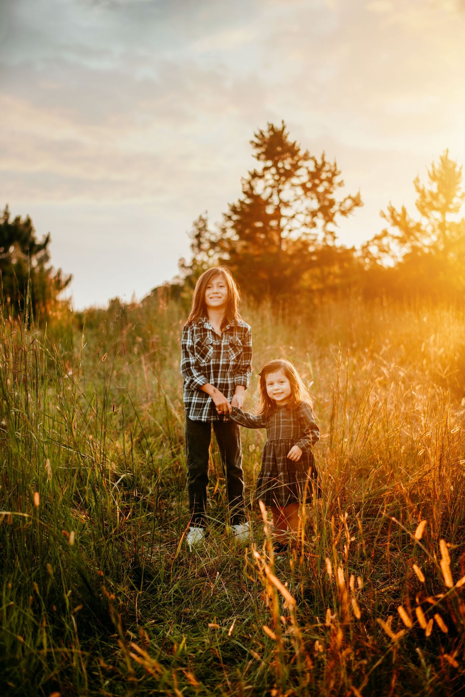Family enjoying a golden sunset moment in a tall grass field during a lifestyle photography session.