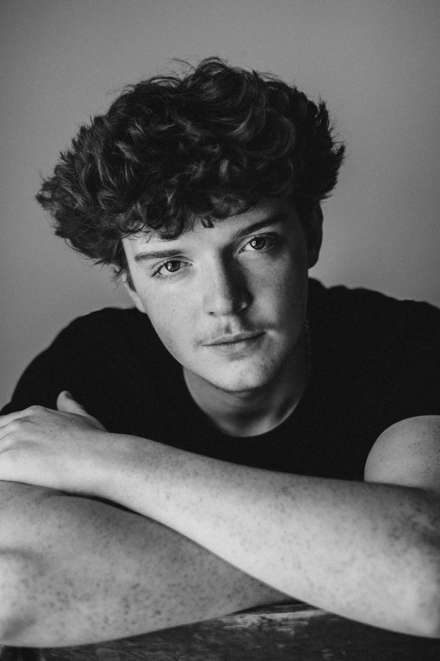 Artistic black and white portrait in moody lighting with dramatic shadows.