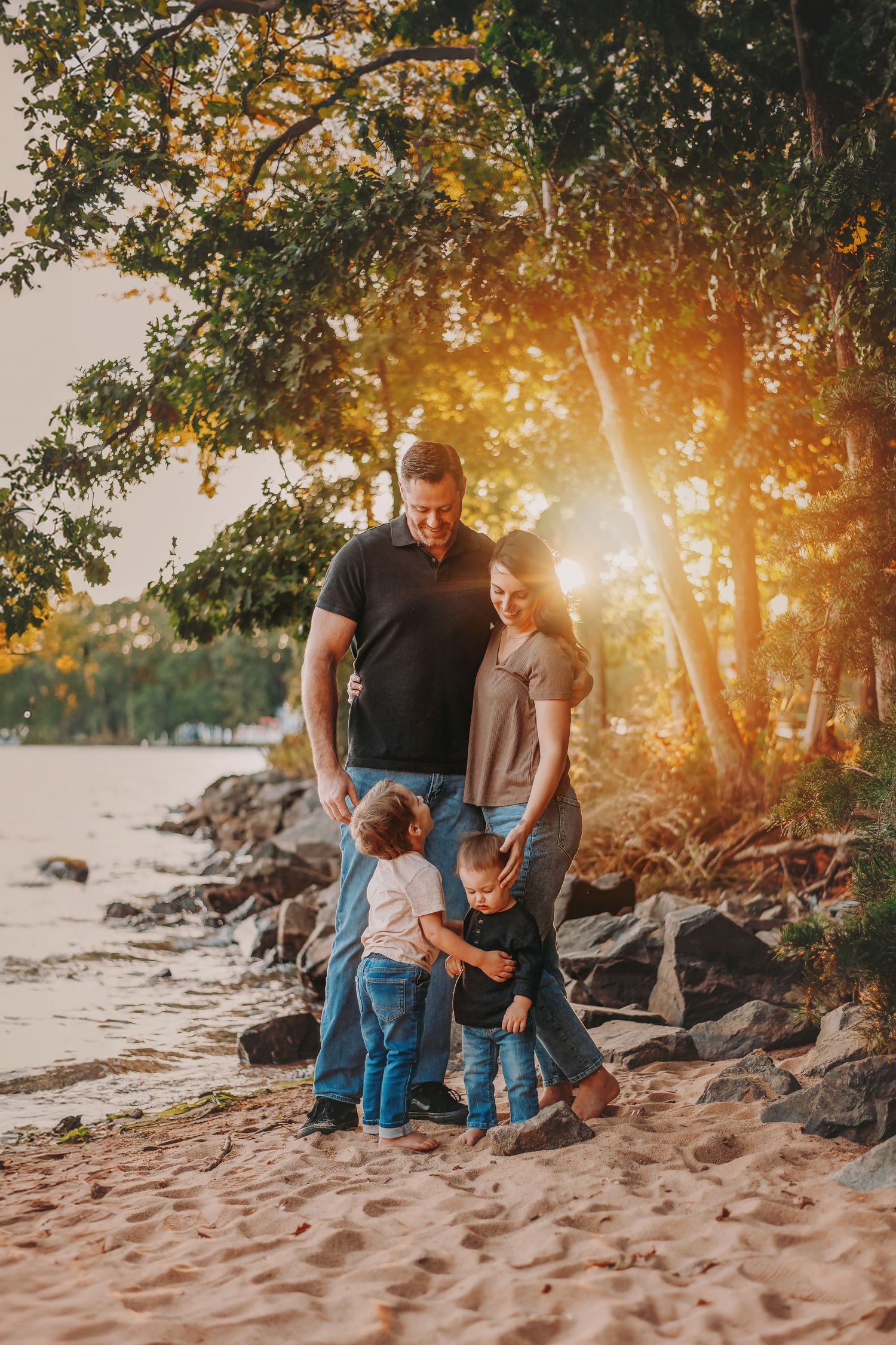 Family enjoying sunset at Lake Norman shore with trees casting golden light in the background.
