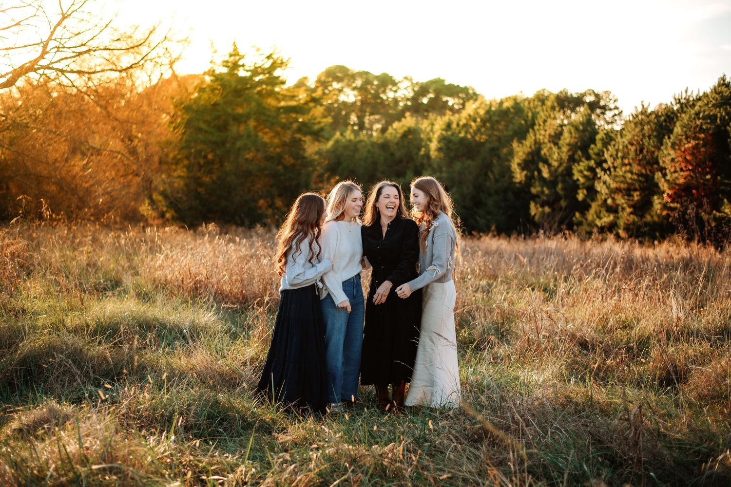 Friends gather in golden field during sunset for outdoor portrait session.