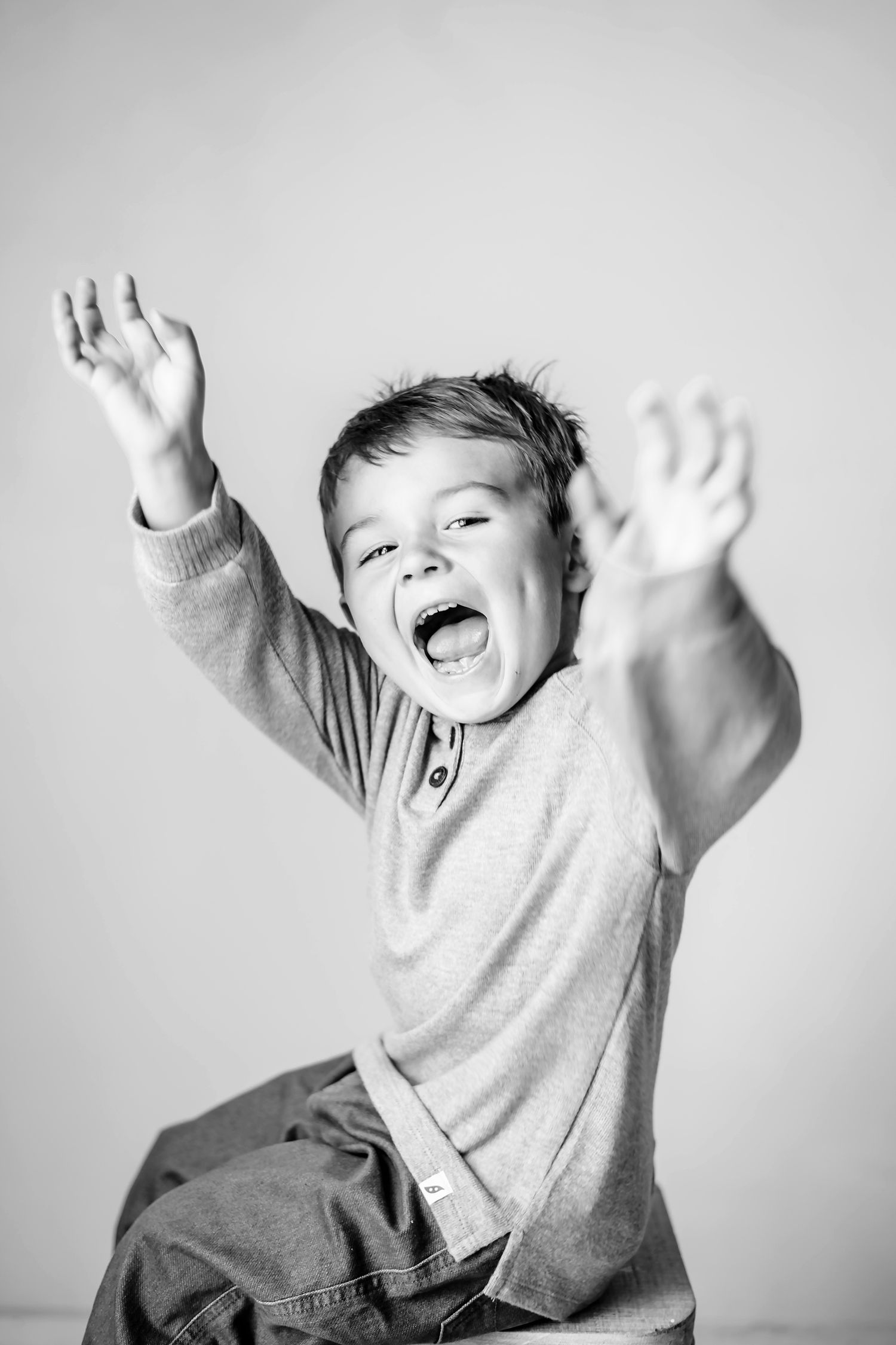 Energetic child jumping with arms raised in black and white photo.