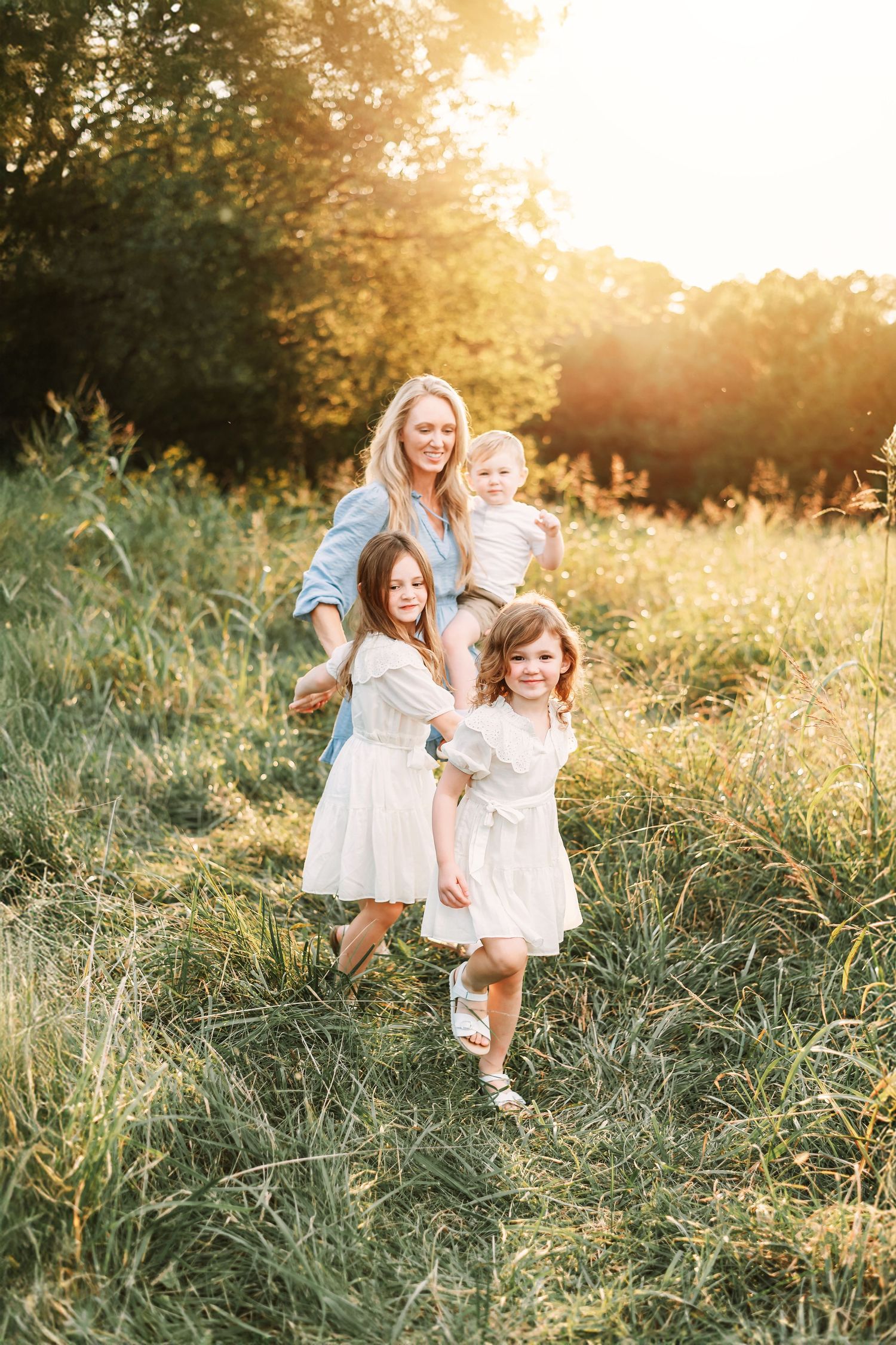 Group dancing together in sunlit meadow wearing flowing white dresses.